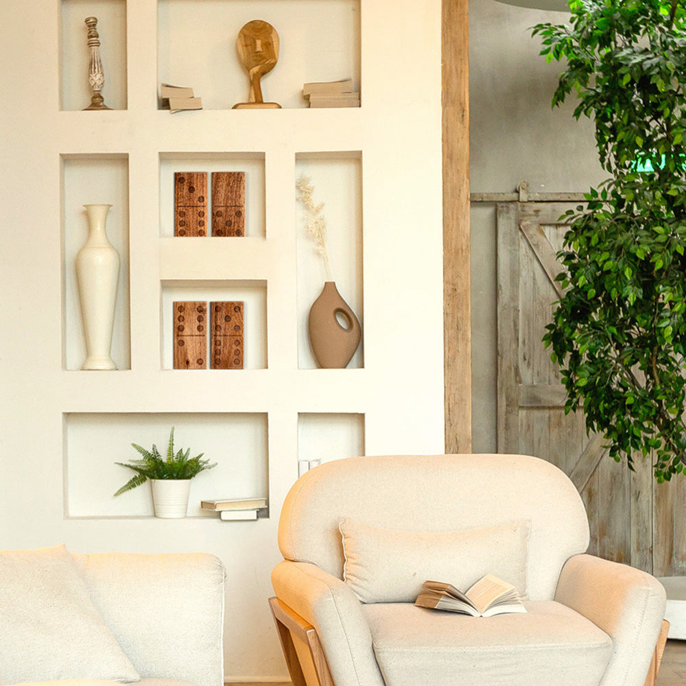 Living room with a beige armchair, white wall with decorative items, and a plant.