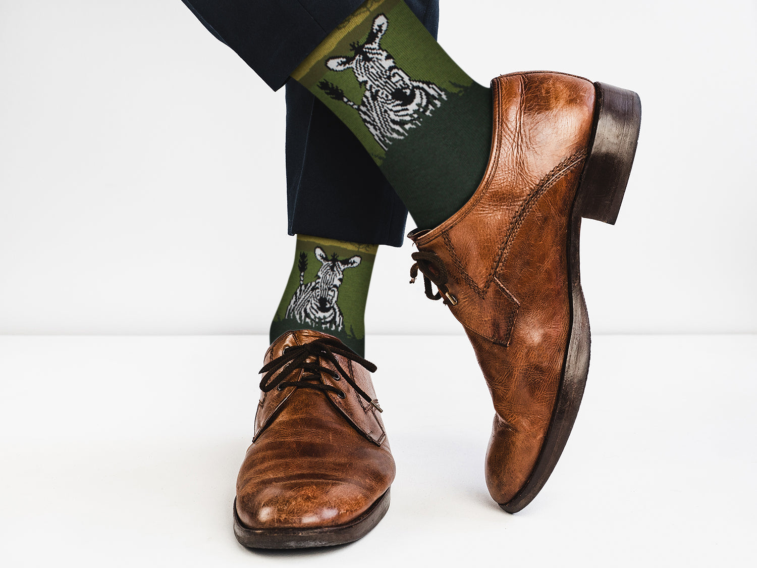 Brown dress shoes and green socks with zebra pattern on a white background