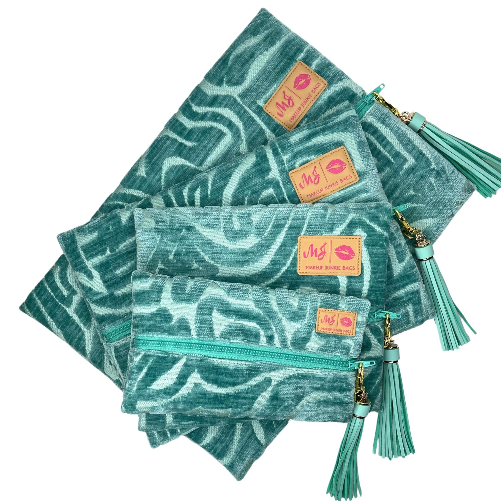 Set of teal patterned pouches with tassels and visible brand label on a white background