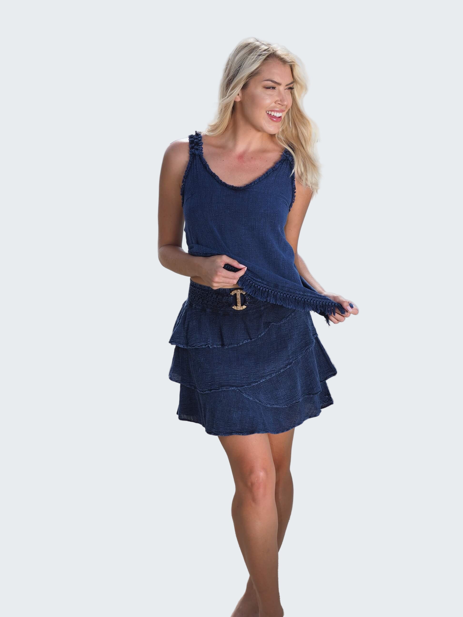 Woman in a blue dress standing on a beach with water in the background