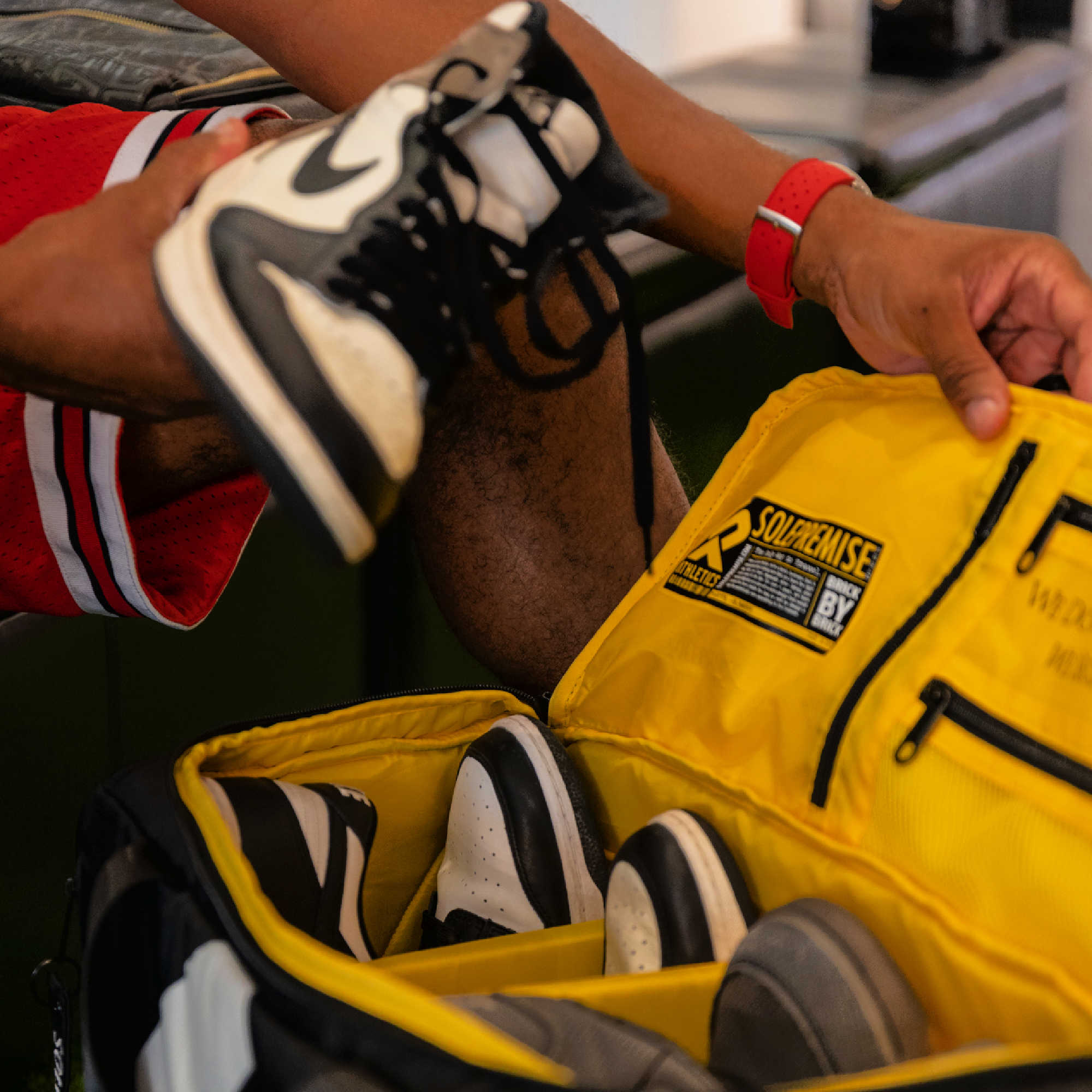 Person holding a black and white sneaker above a yellow bag with 'Supreme' branding.
