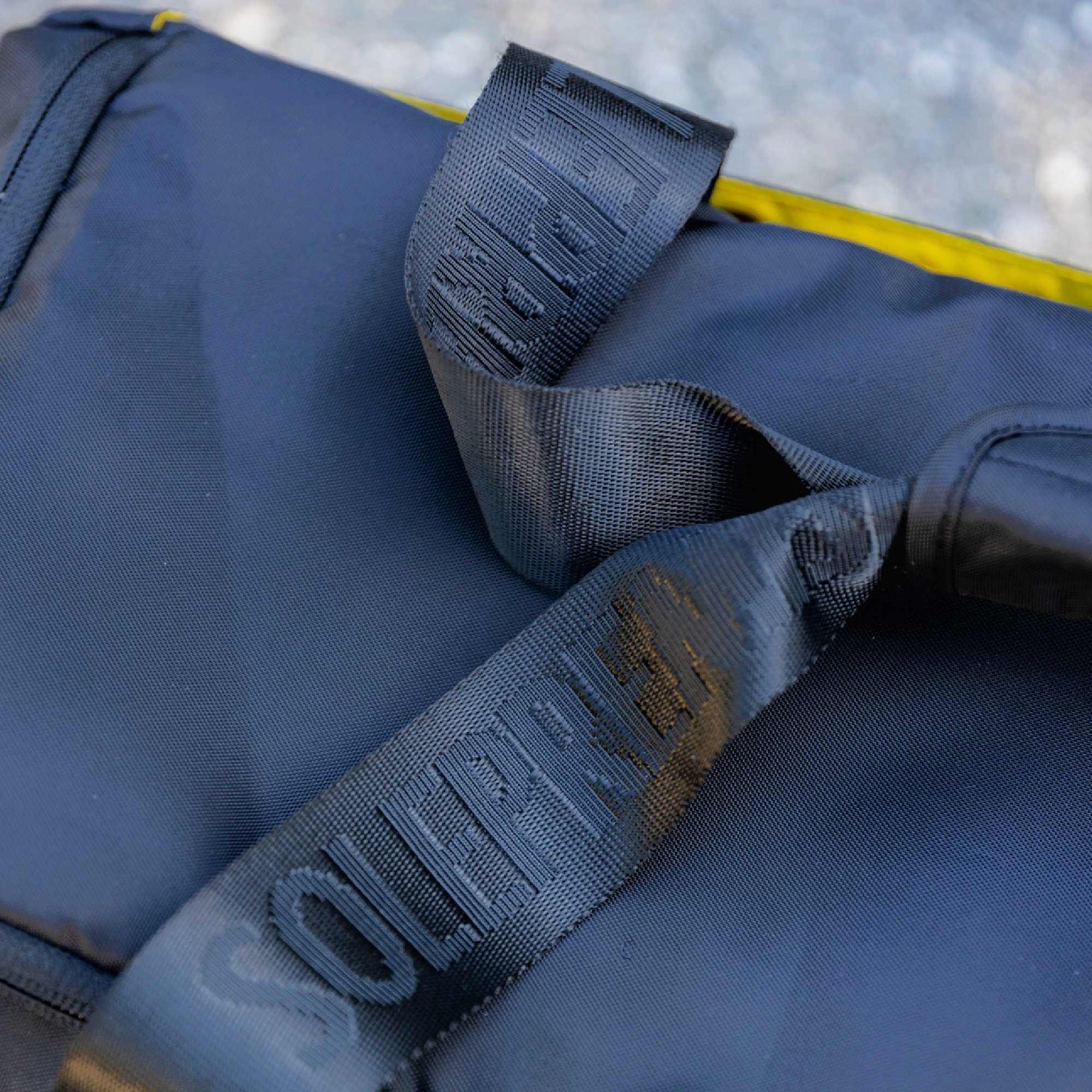 Close-up of a blue bag with a black strap featuring 'Squid Industries' branding.