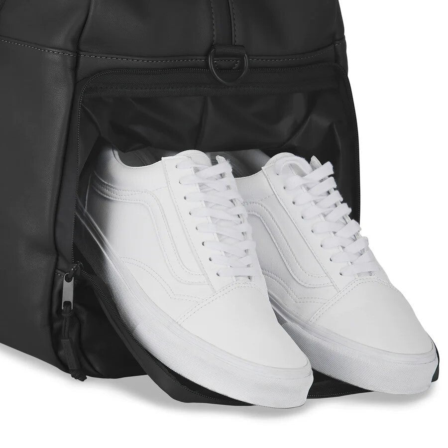 White sneakers being placed into a black backpack