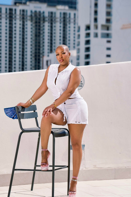 Woman in a white outfit sitting on a chair with cityscape in the background