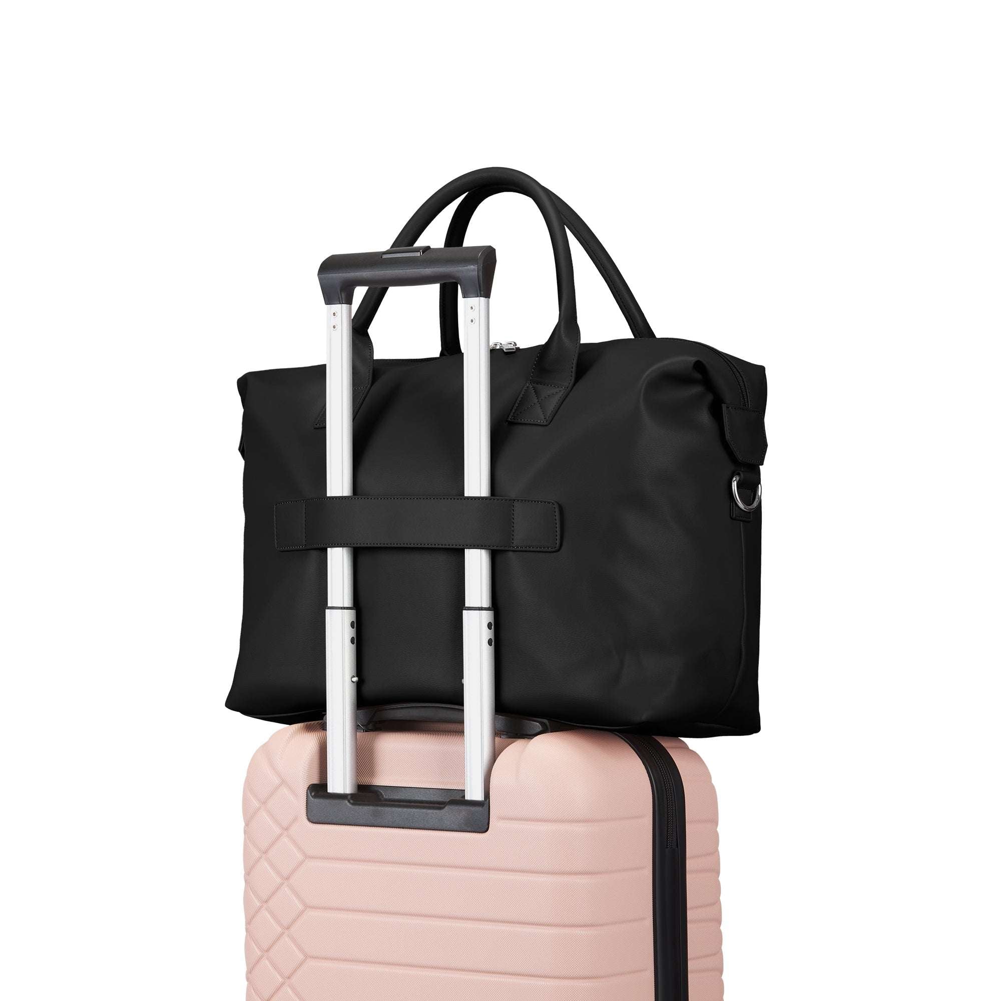 Black travel bag with a handle on top of a pink suitcase against a white background