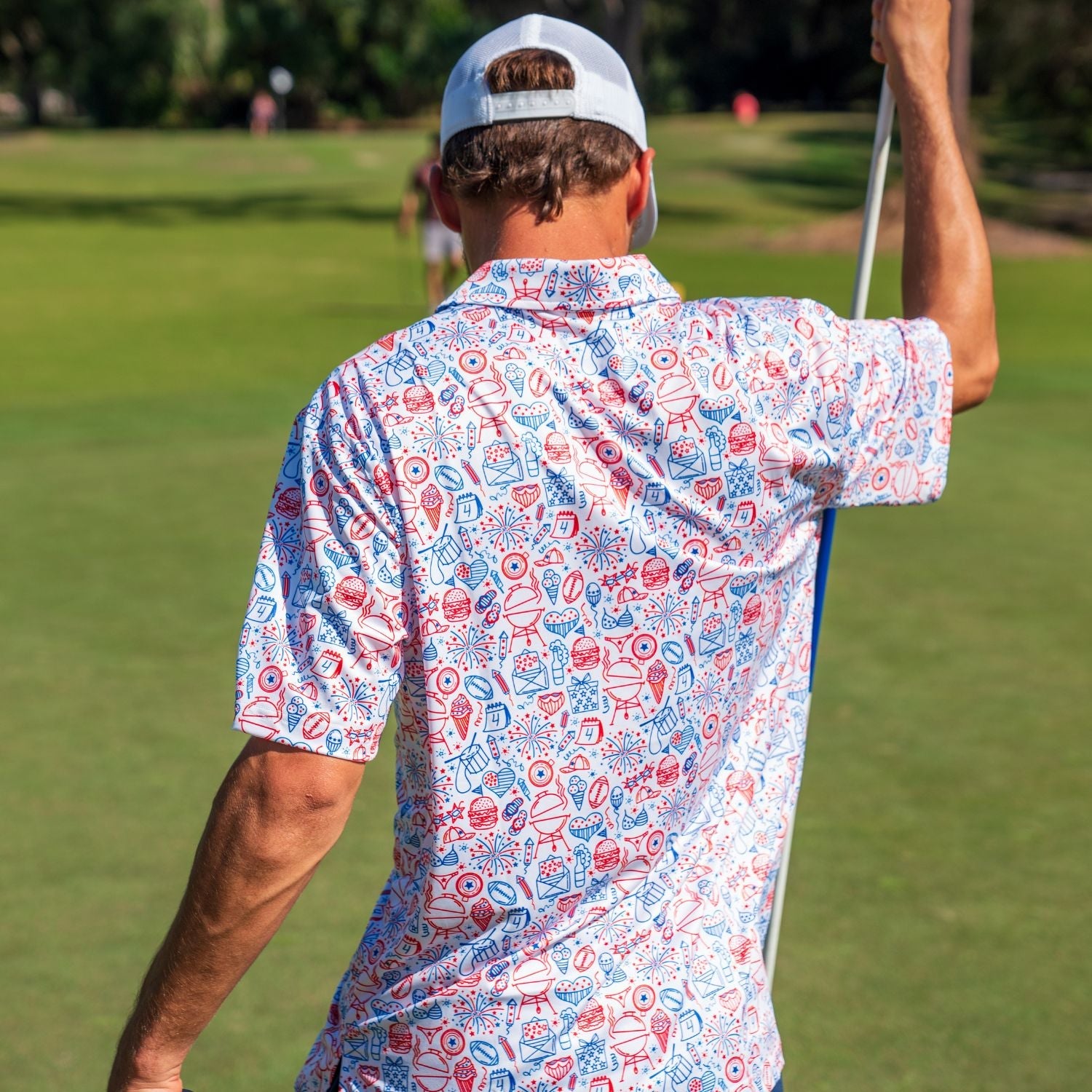 Man in a patterned shirt and cap playing golf on a green course