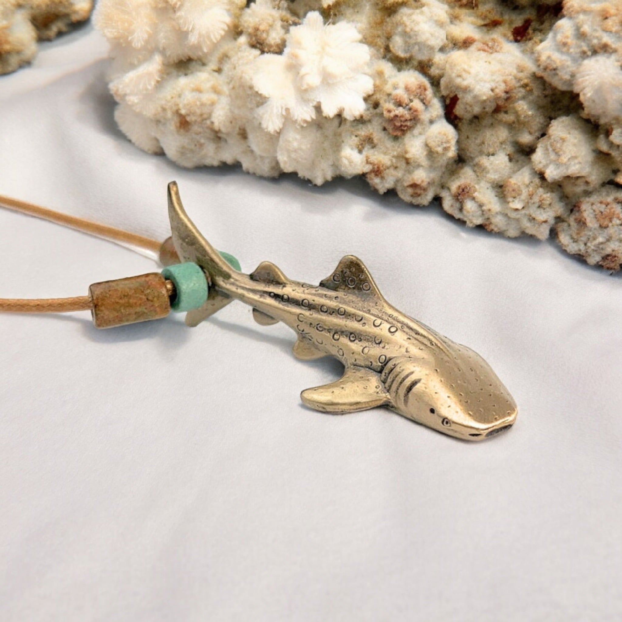 Bronze shark pendant on a cord with coral in the background