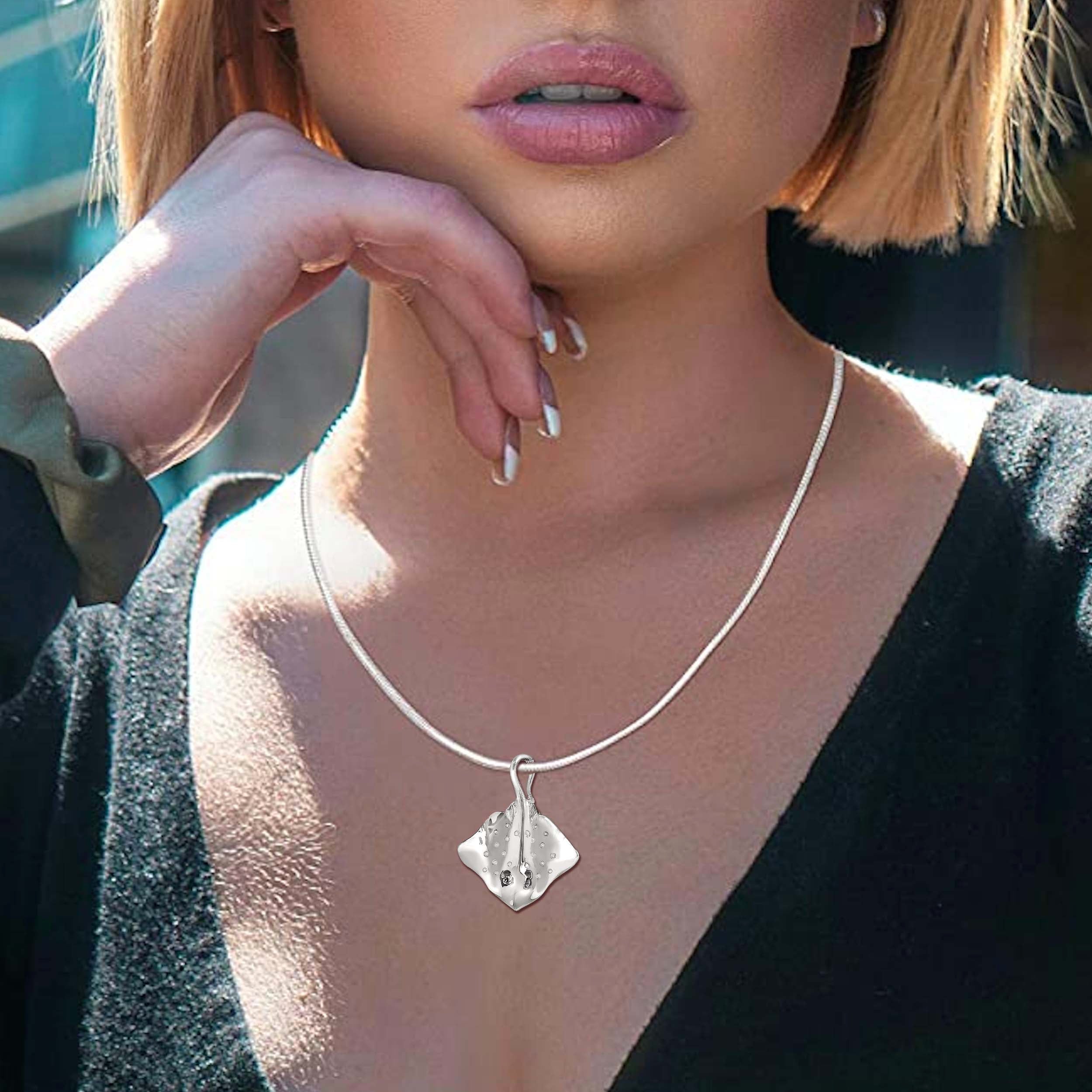 Close-up of a person wearing a silver necklace with a pendant.