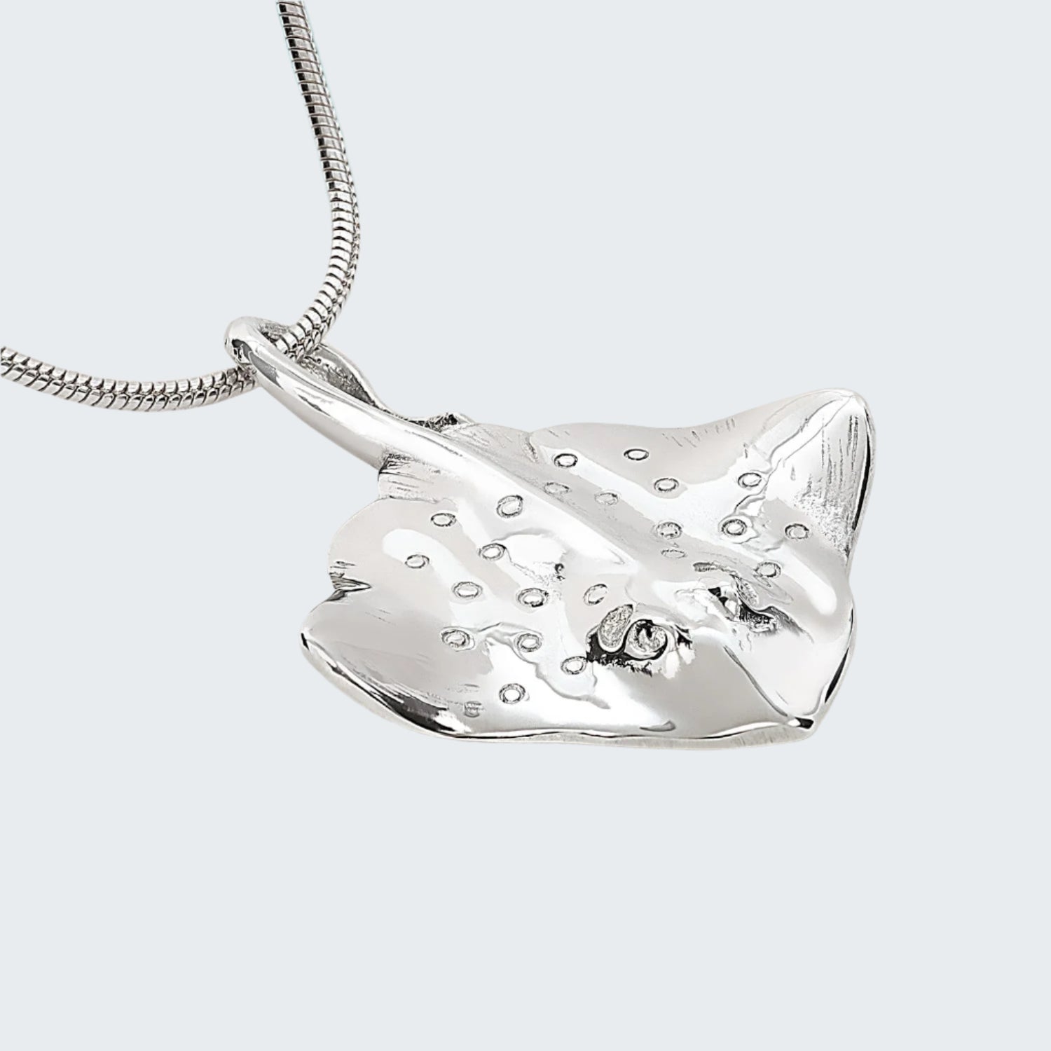 Silver stingray pendant on a chain against a light gray background