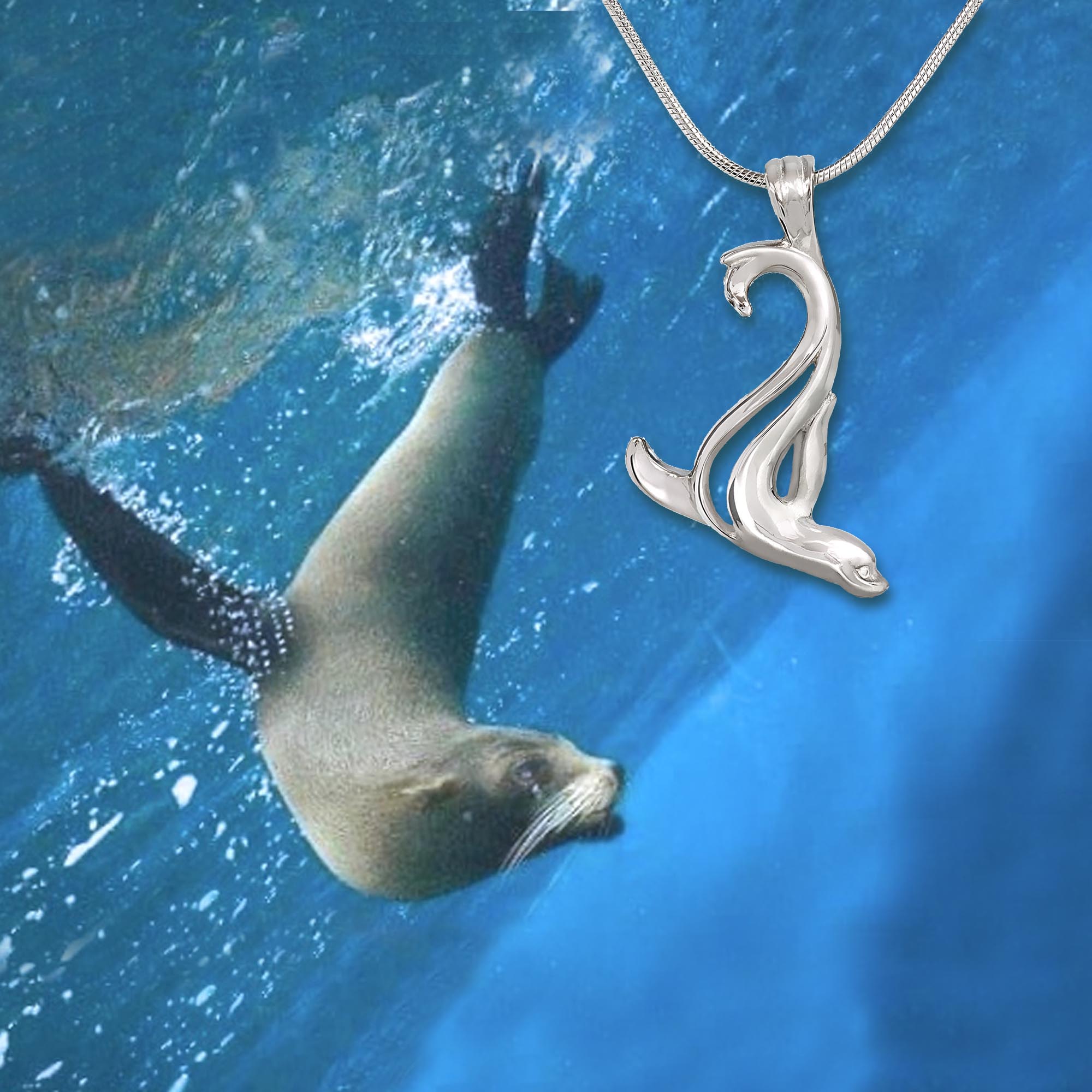 Silver pendant shaped like a seal swimming next to a real seal underwater.