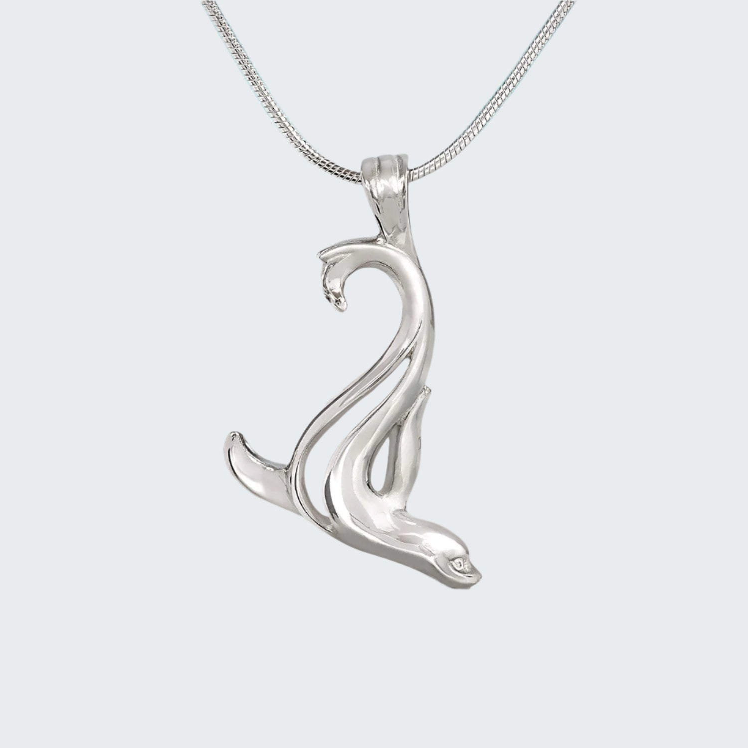 Silver dolphin pendant on a chain with a beach background