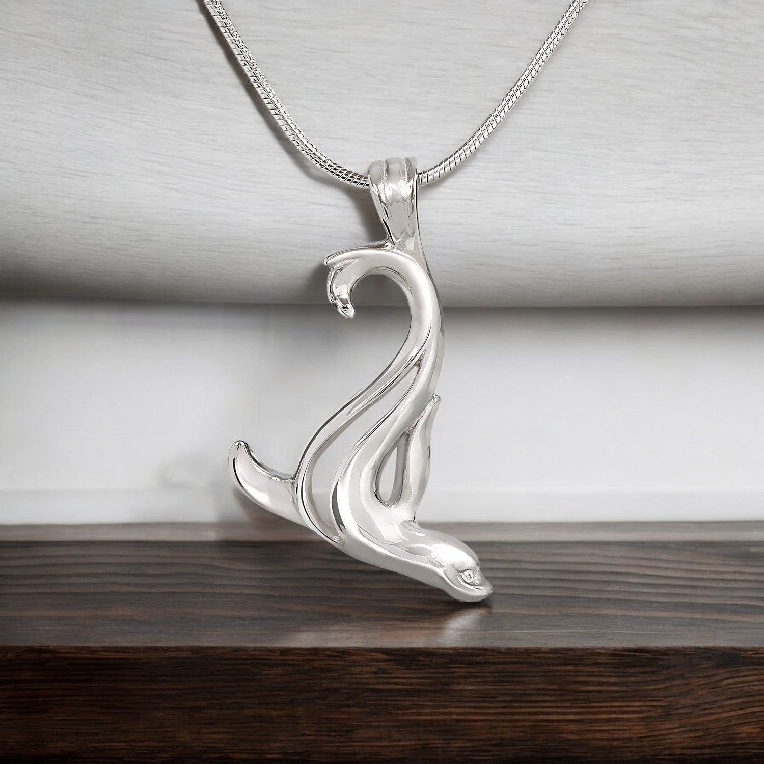 Silver snake pendant on a chain against a neutral background