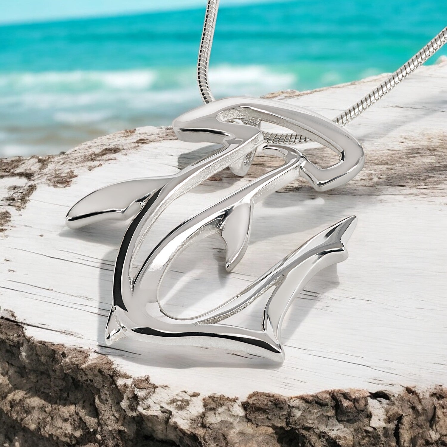Silver anchor pendant on a chain with a beach background