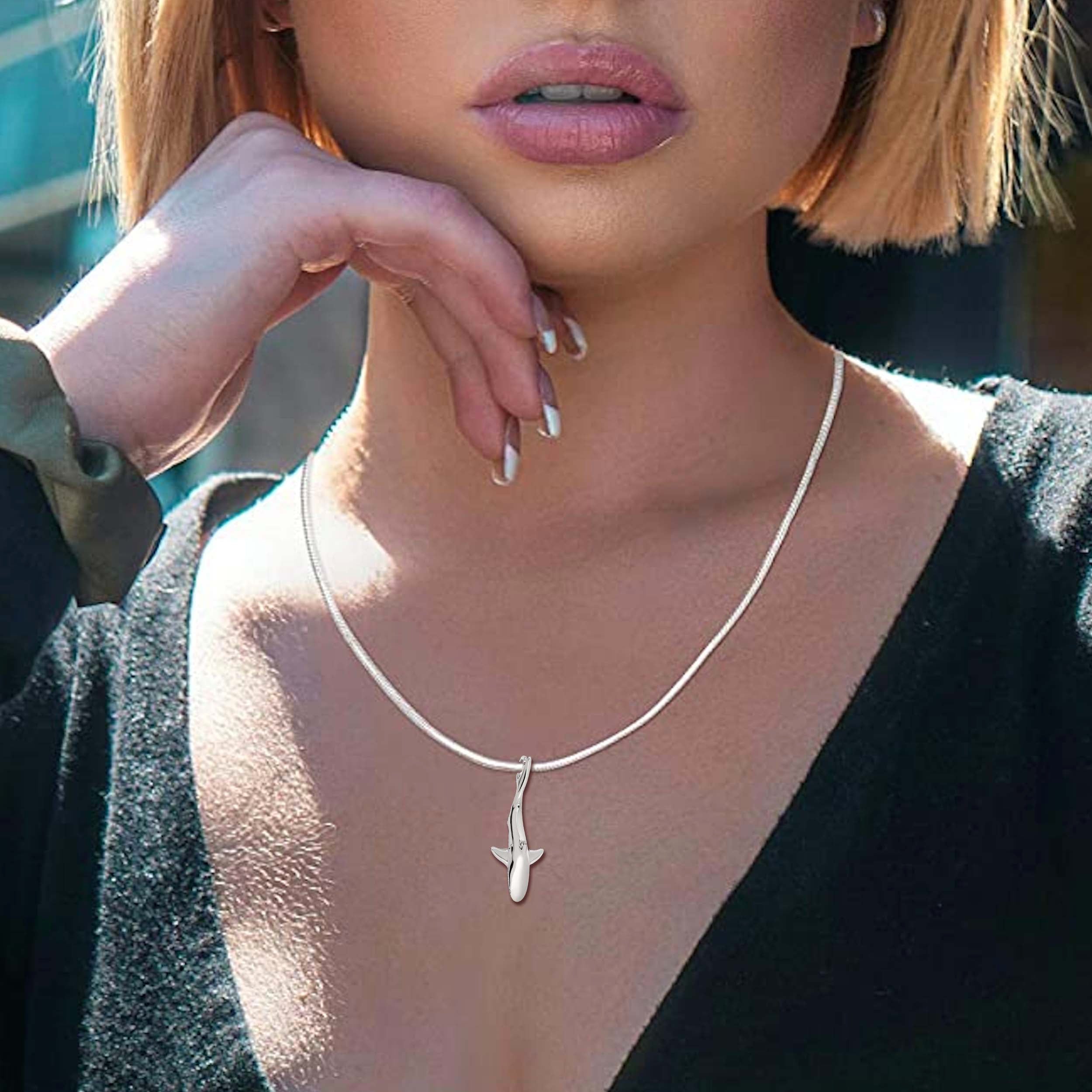 Close-up of a person wearing a silver necklace with a pendant.