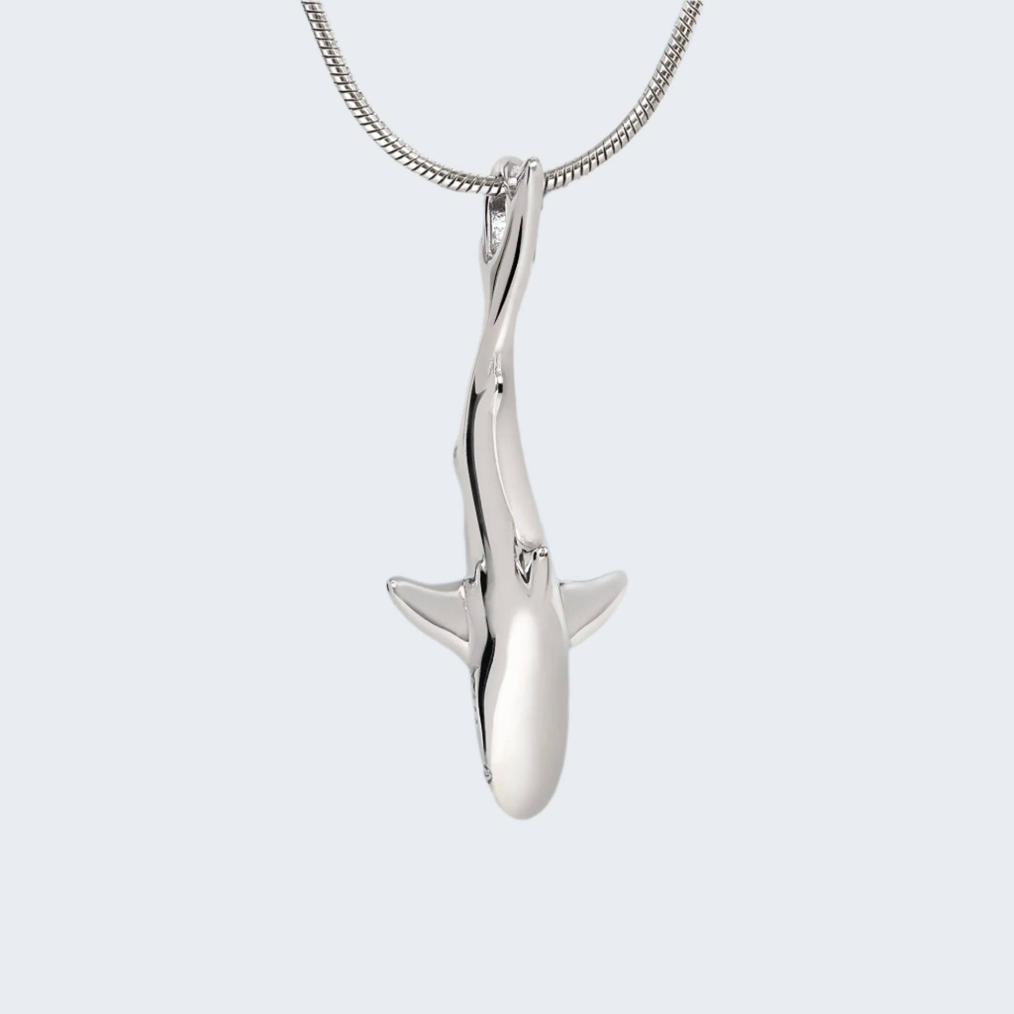 Silver shark pendant on a chain against a light gray background