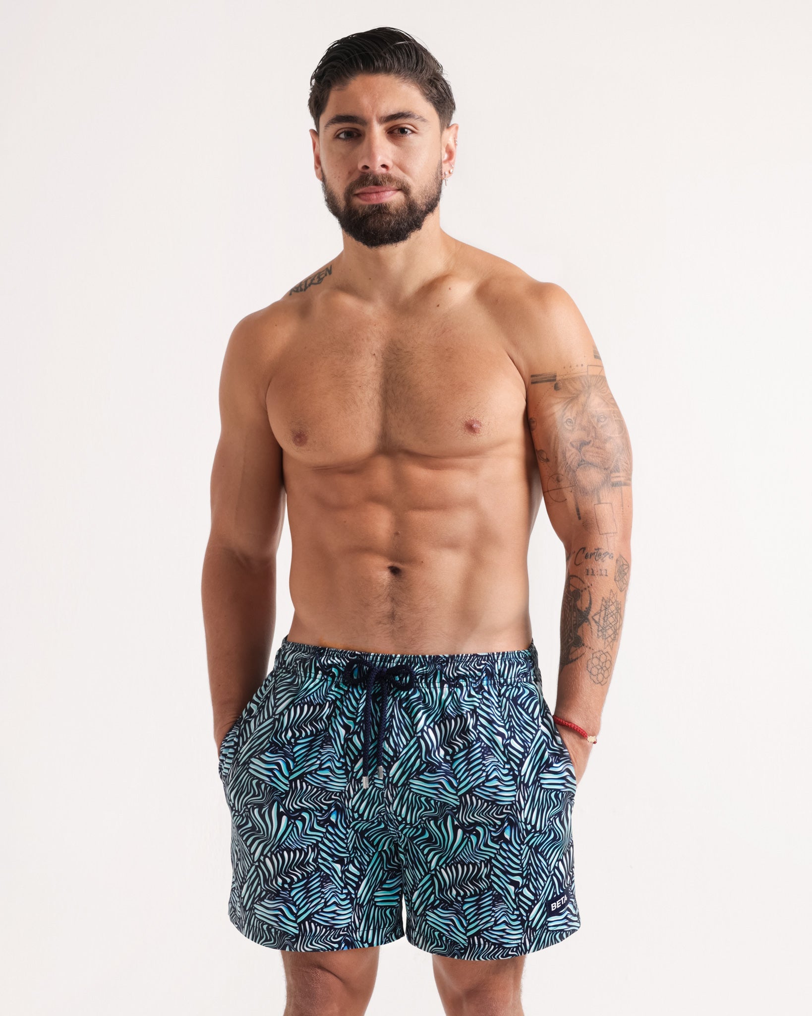 Man wearing blue patterned swim shorts on a white background