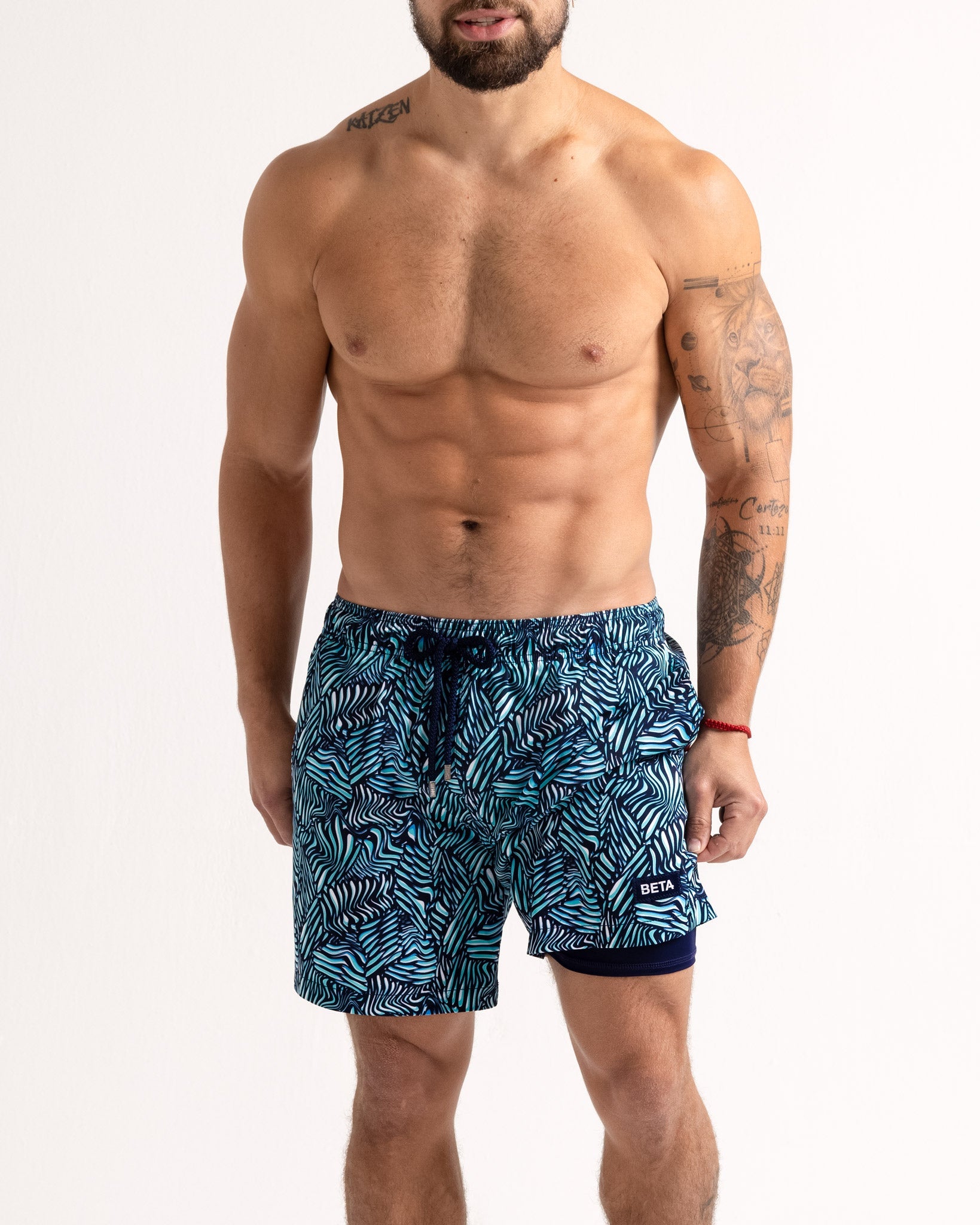 Man wearing blue patterned swim shorts on a white background