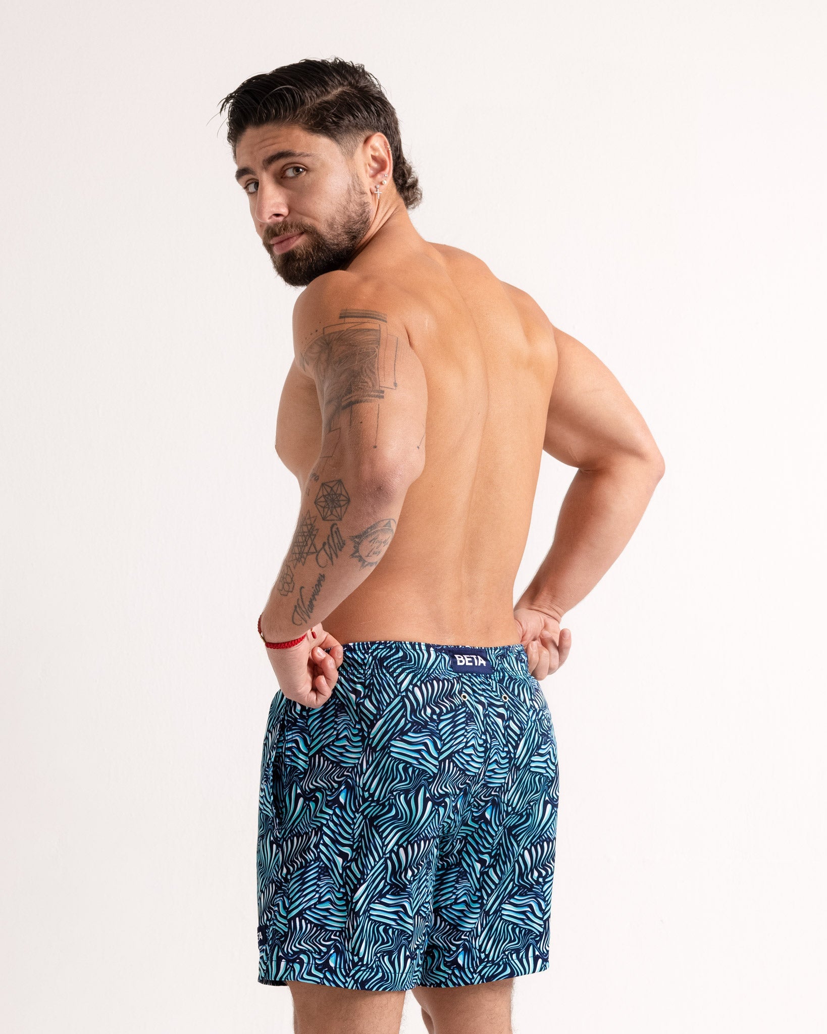 Man wearing blue patterned swim shorts on a white background