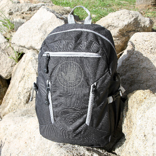 Black backpack with a logo on a rock surface