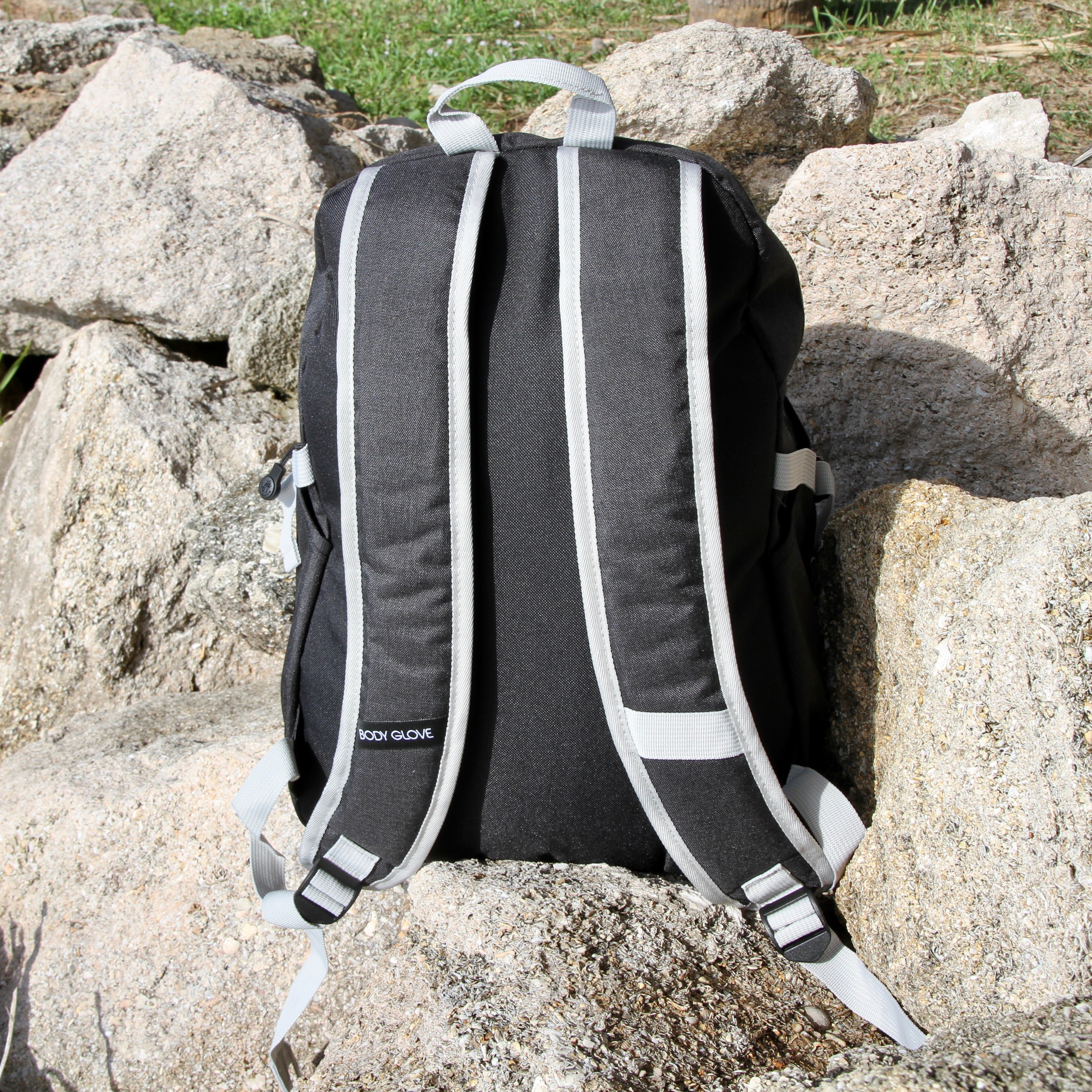 Black backpack with white straps on a rocky surface