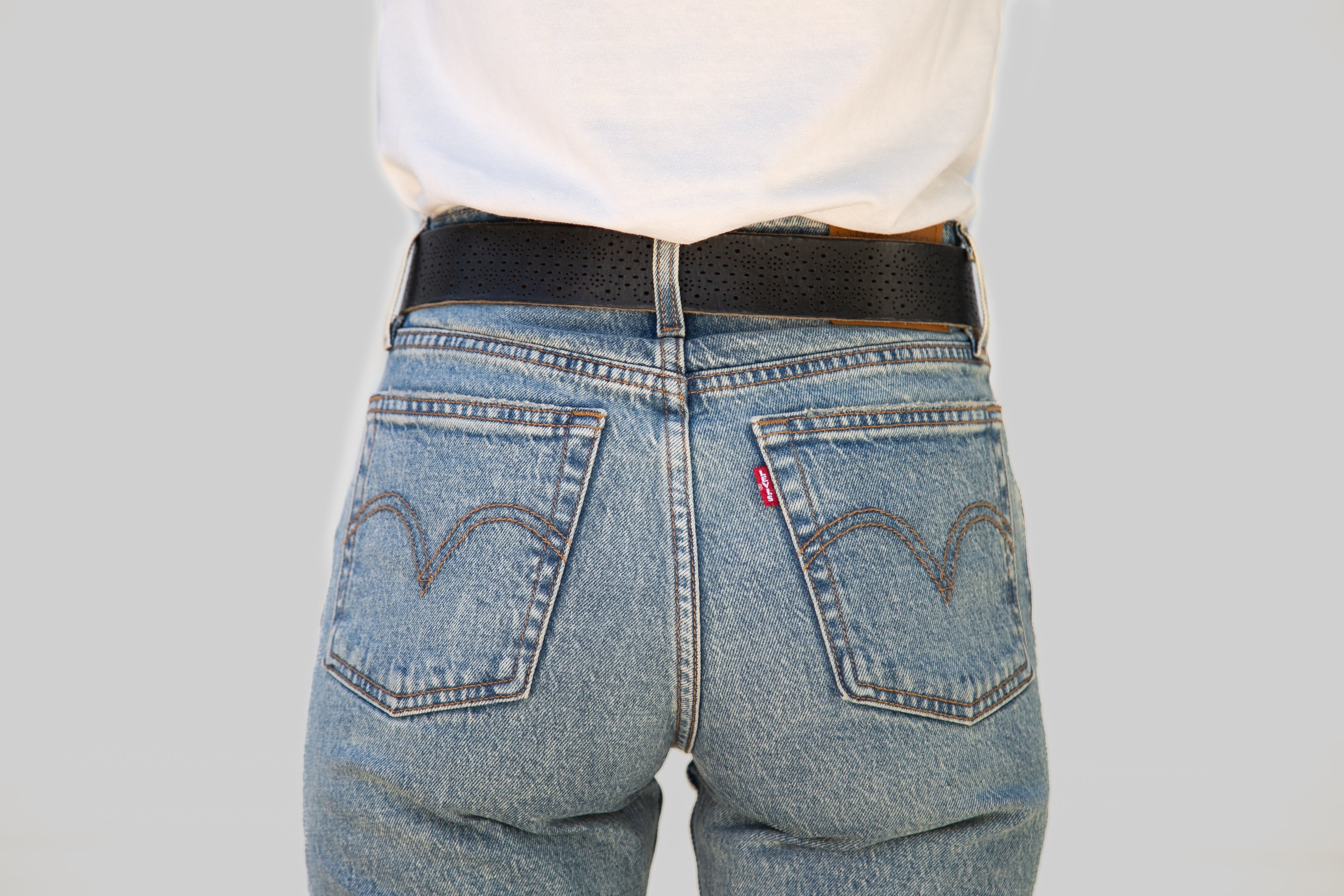 Person wearing blue jeans with a Levi's logo on a plain background