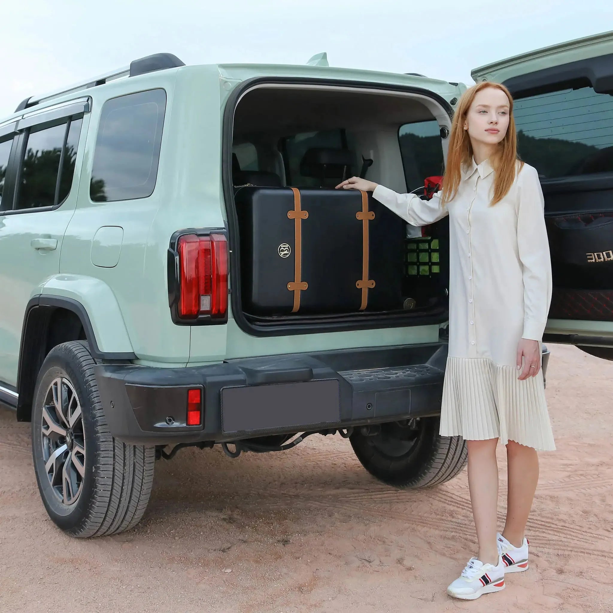 Woman holding a suitcase next to an open car trunk