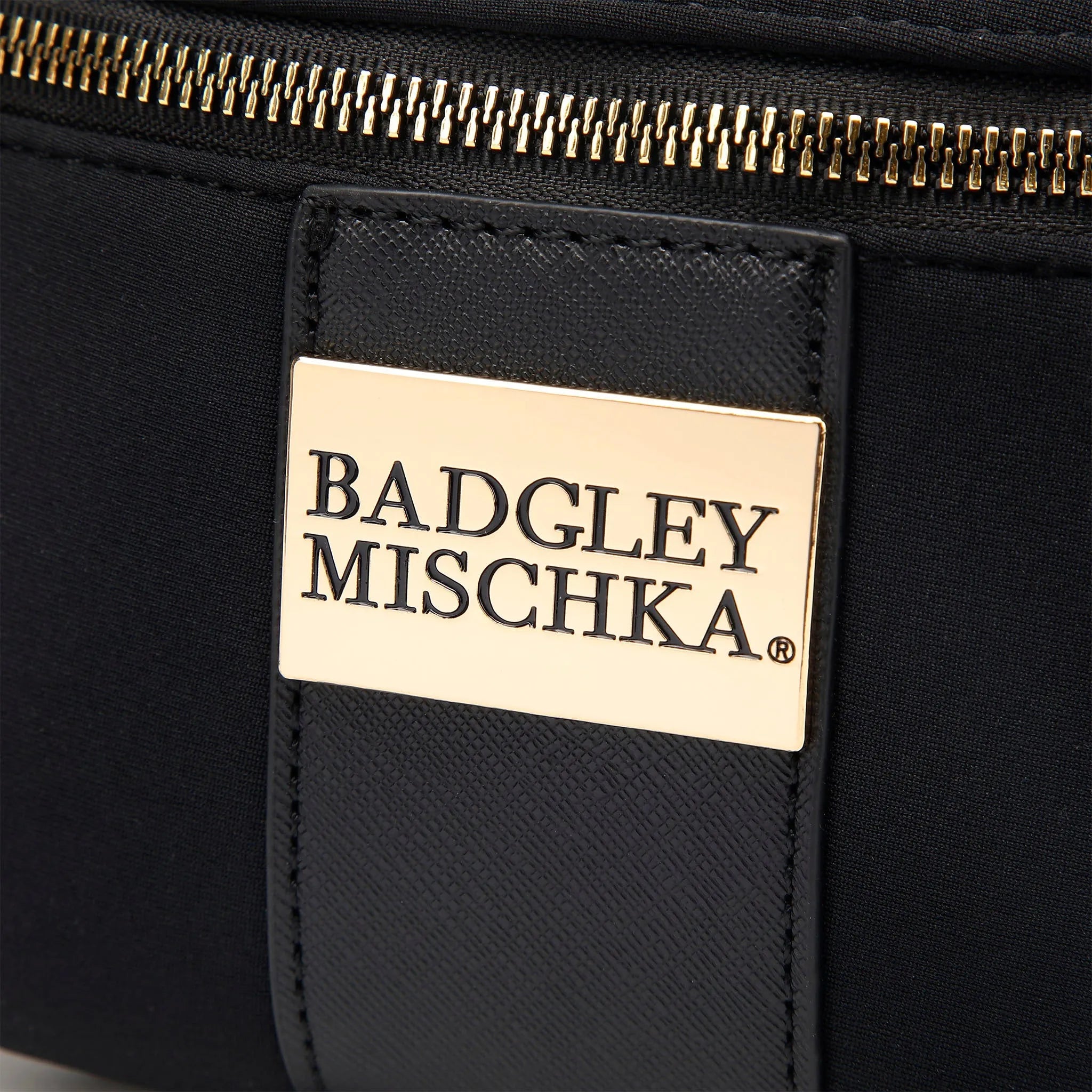 Close-up of a black bag with a gold zipper and Badgley Mischka label.