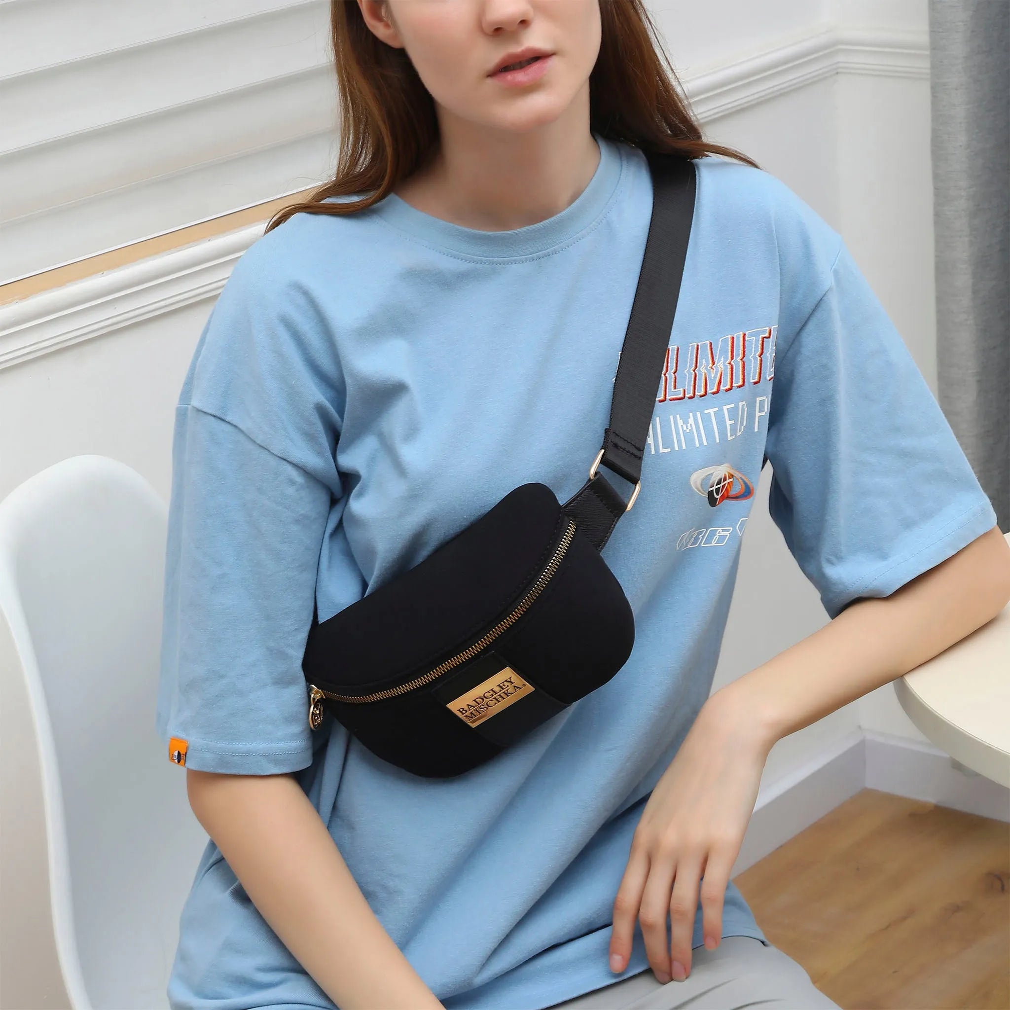 Person wearing a blue t-shirt with text and a black waist bag.