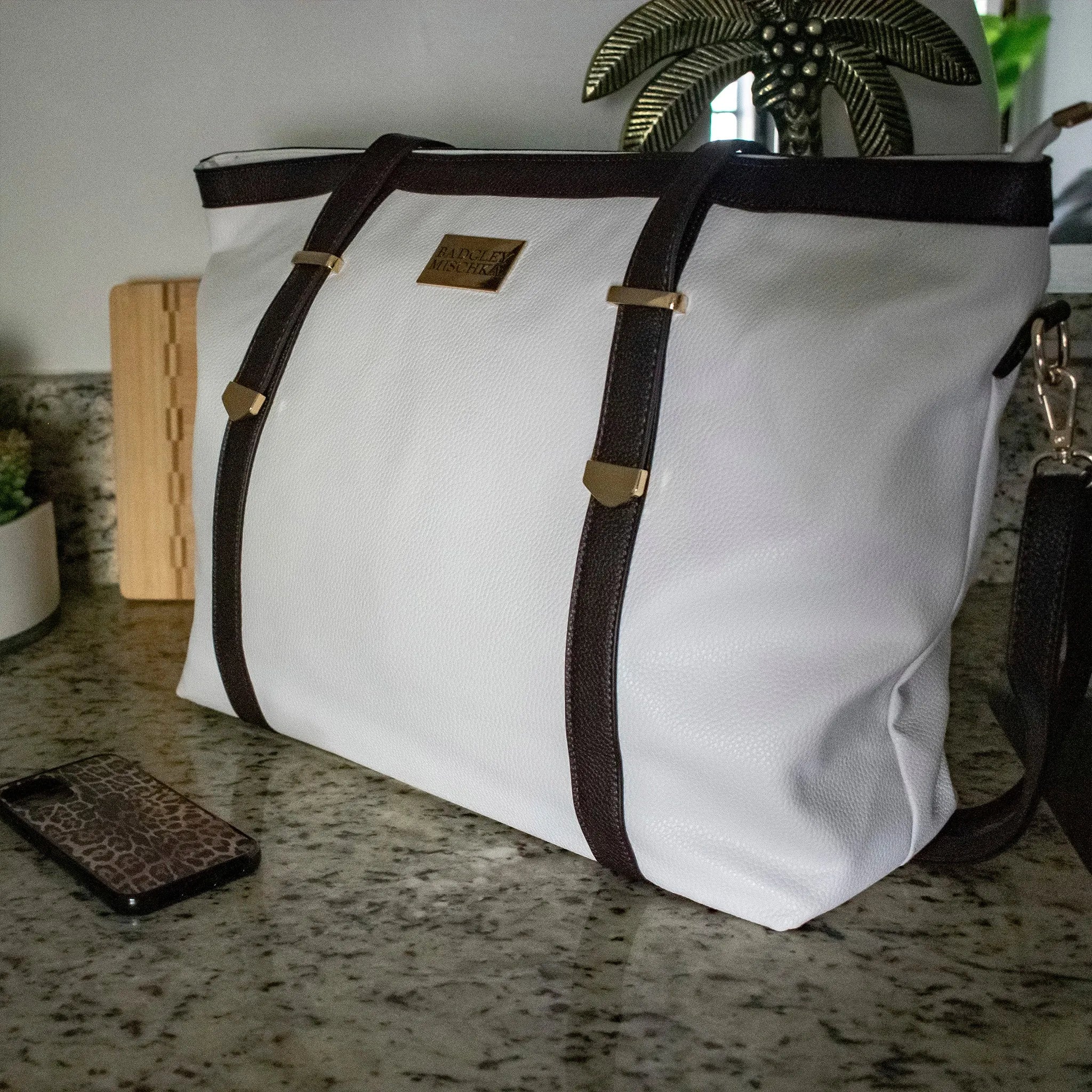 White bag with brown straps on a countertop