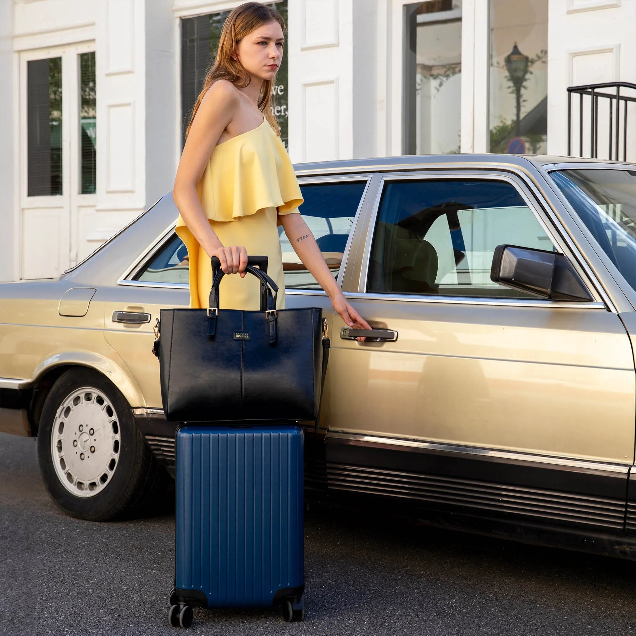 Woman with a suitcase and handbag standing next to a car