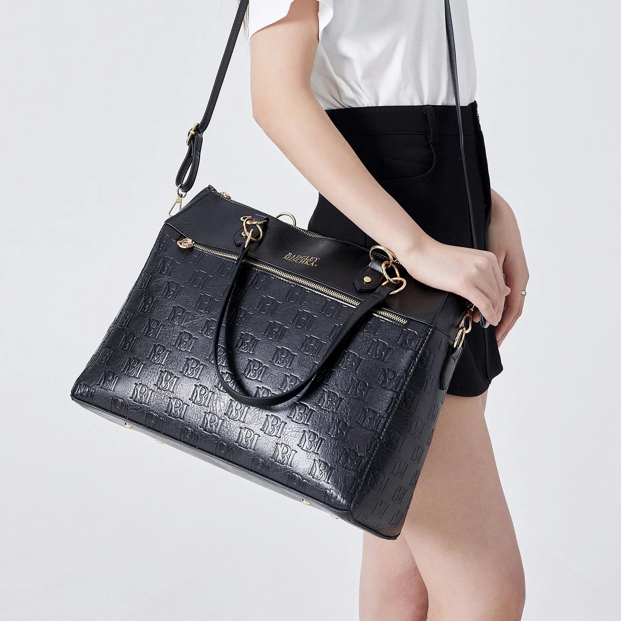 Black textured handbag held by a person on a white background
