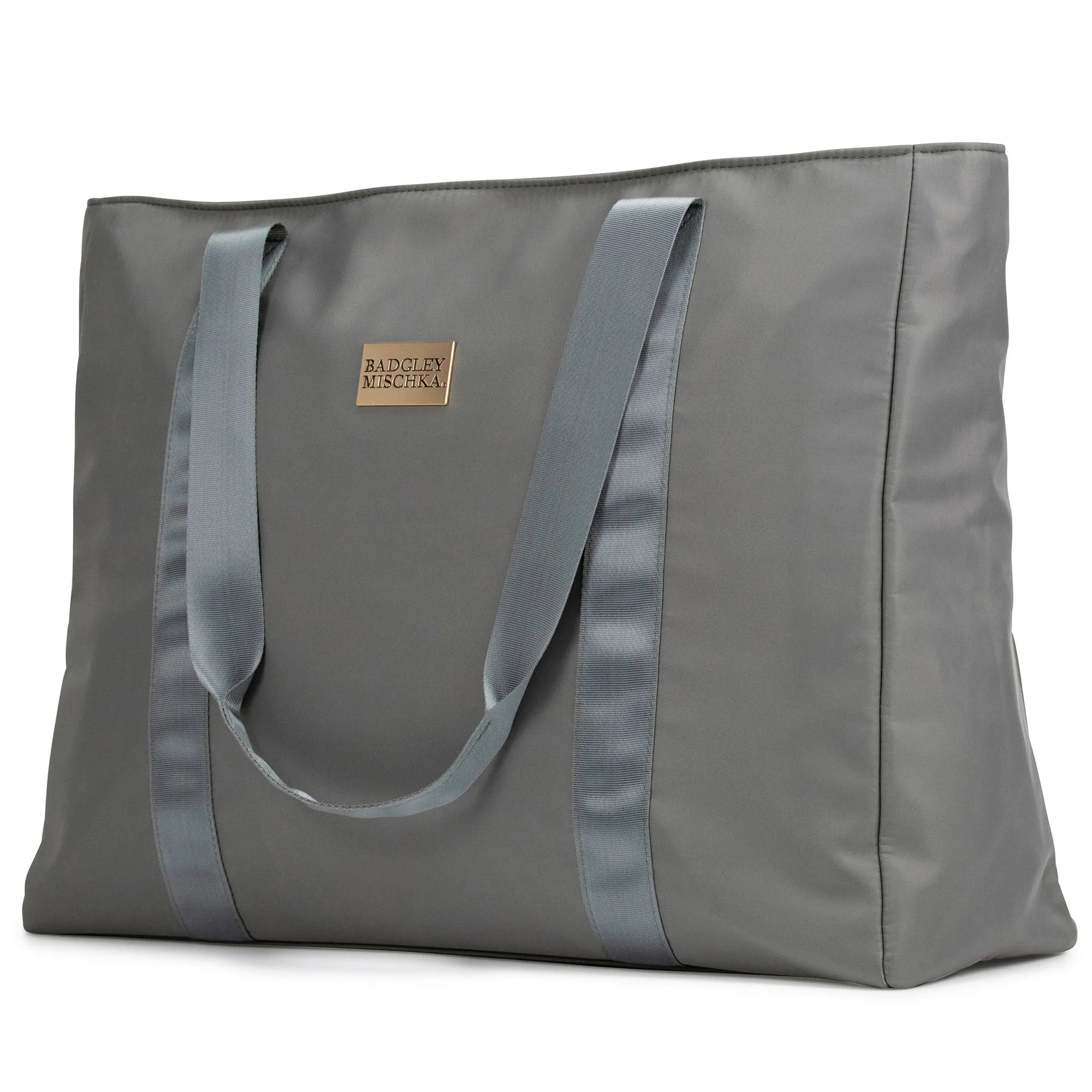 A black nylon tote bag with a shiny gold logo plate, soft webbing straps, and a zippered rear pocket. The bag is displayed in a way that showcases its spacious design and sleek finish.