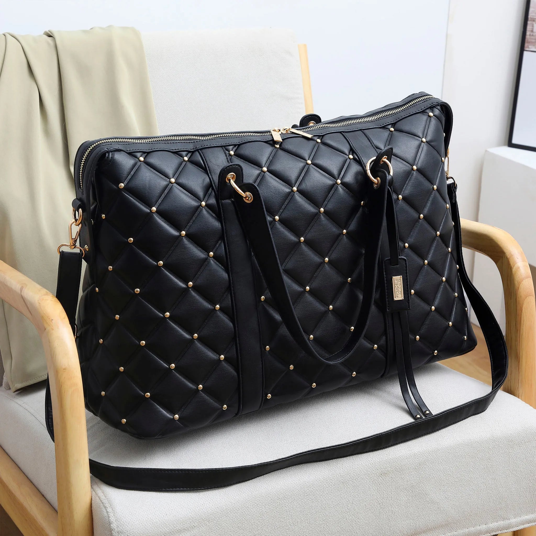 Black quilted handbag with gold studs on a light gray chair