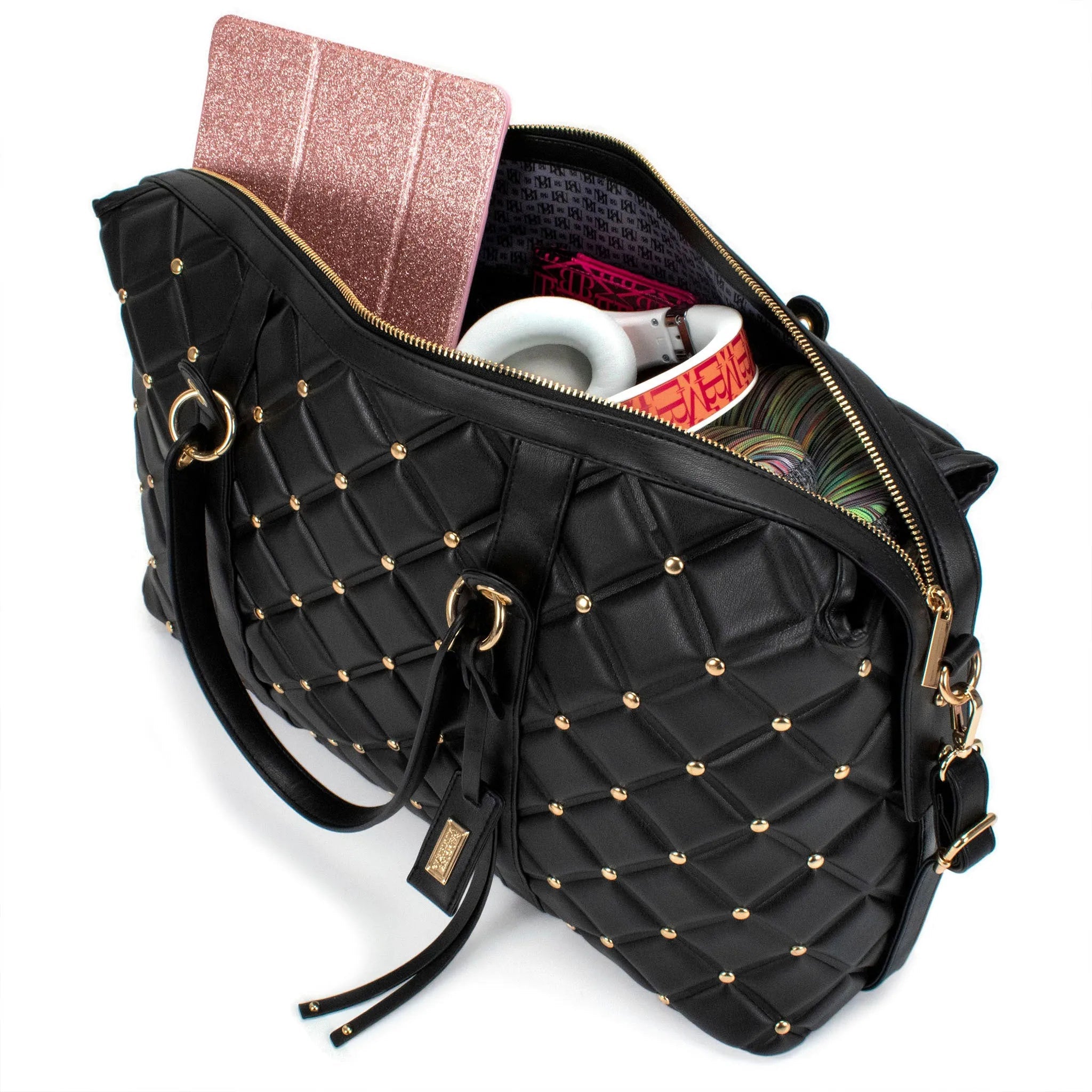 Black quilted handbag with gold studs containing a notebook, mug, and books on a white background