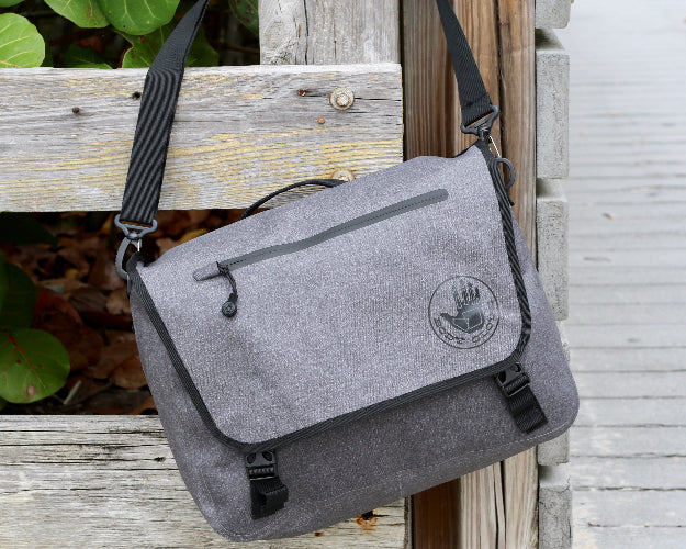 Gray messenger bag with a logo on a wooden post