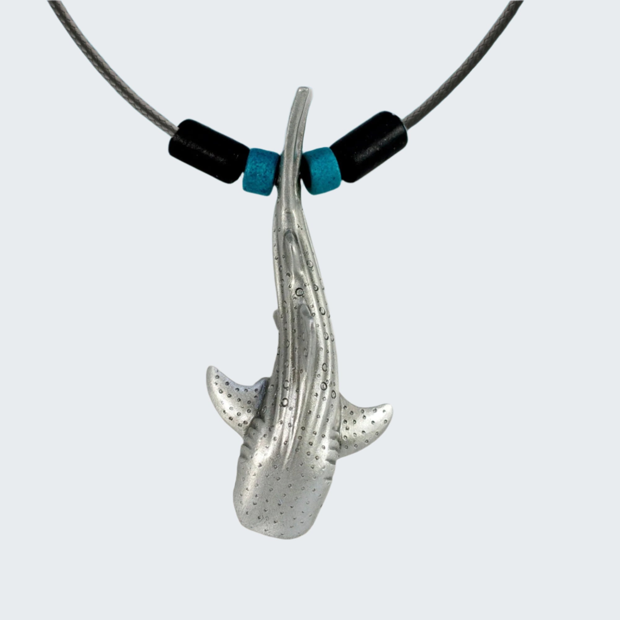 Shark-shaped pendant on a cord with a beach background