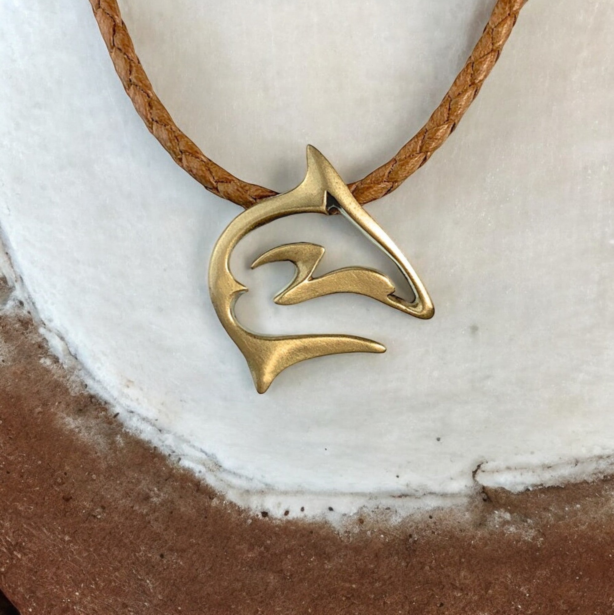 Brass pendant on a leather cord against a white background