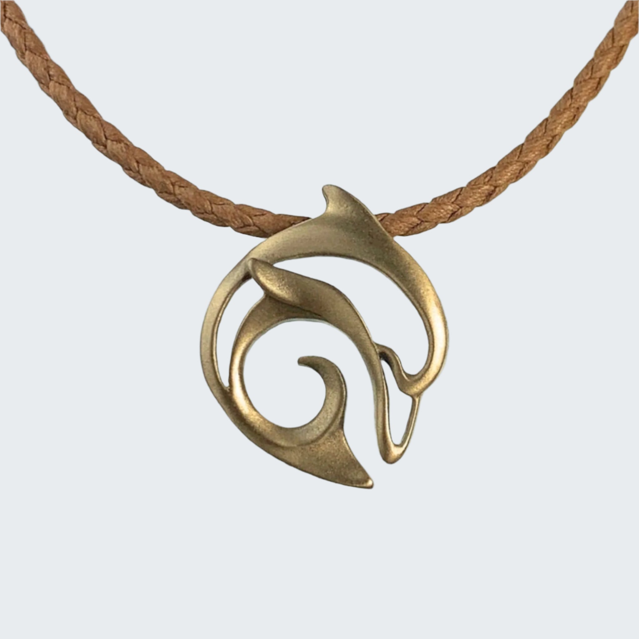 Brass pendant on a brown cord with a beach background