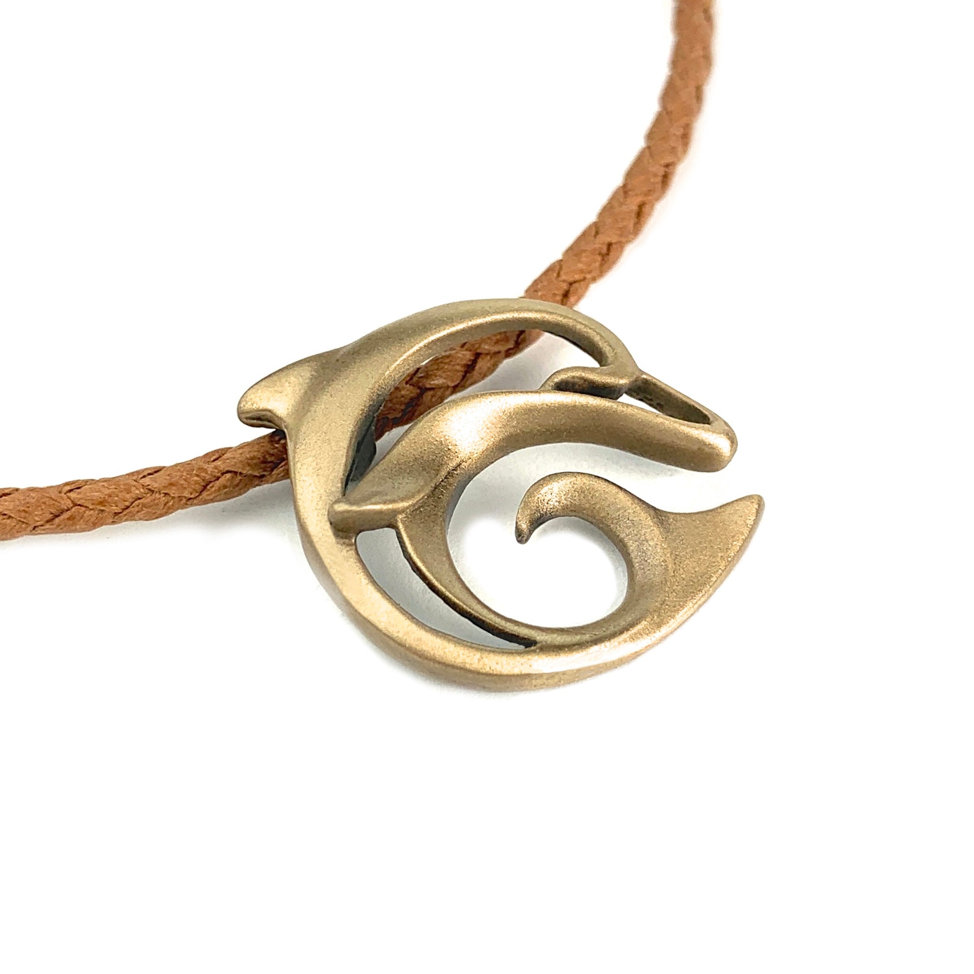 Bronze pendant with wave design on a brown cord against a white background