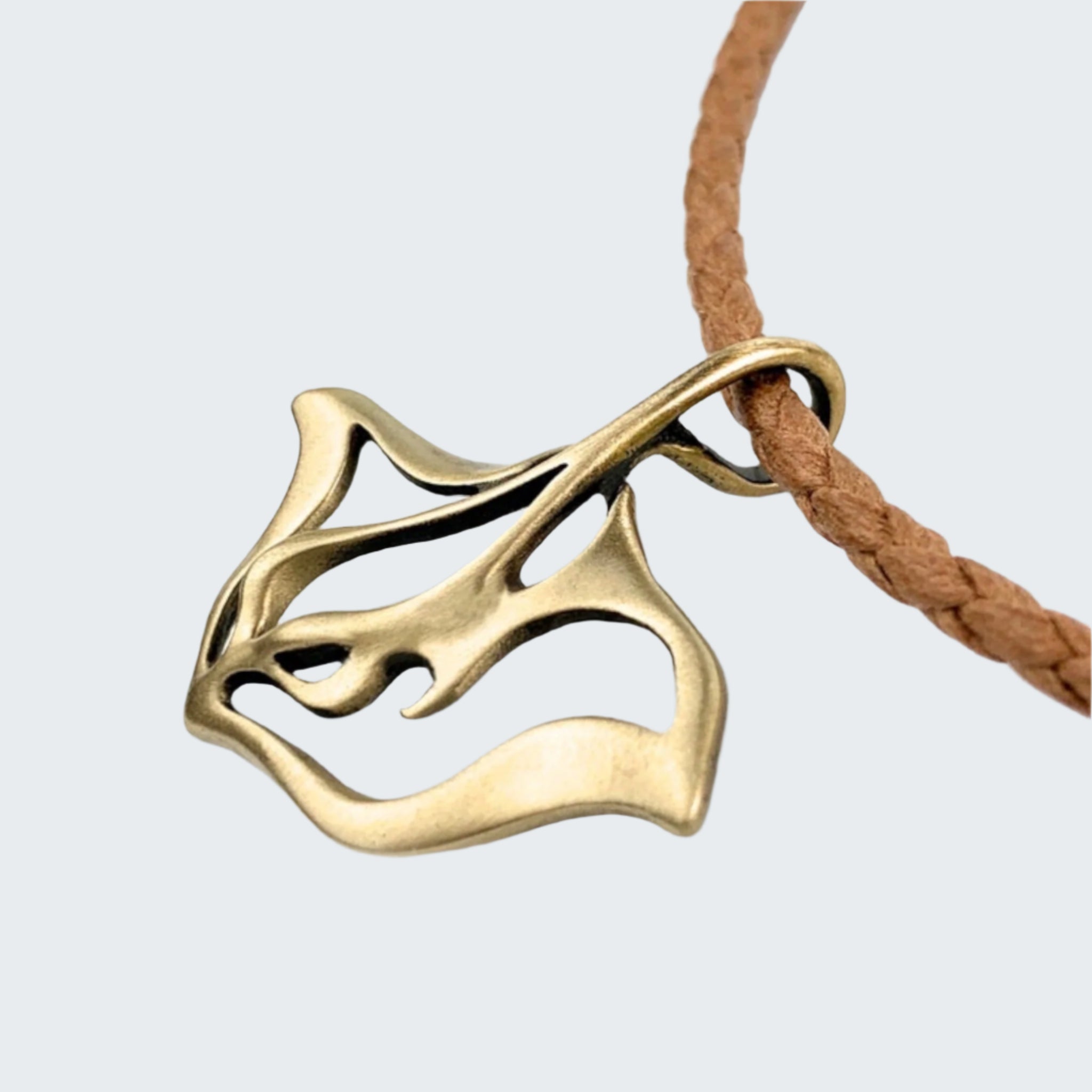 Gold leaf-shaped pendant on a brown cord against a light gray background