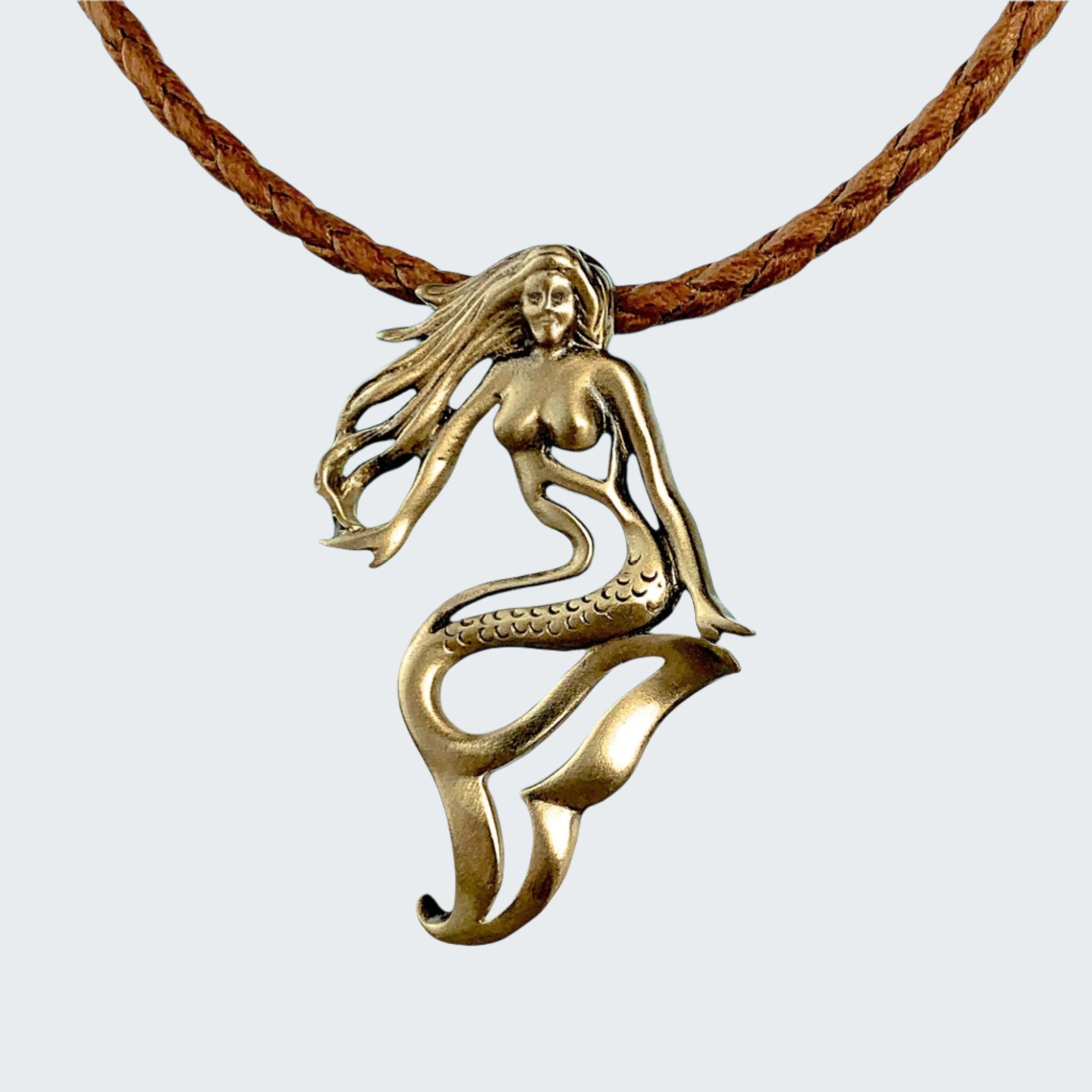 Bronze mermaid pendant on a rope with a beach background