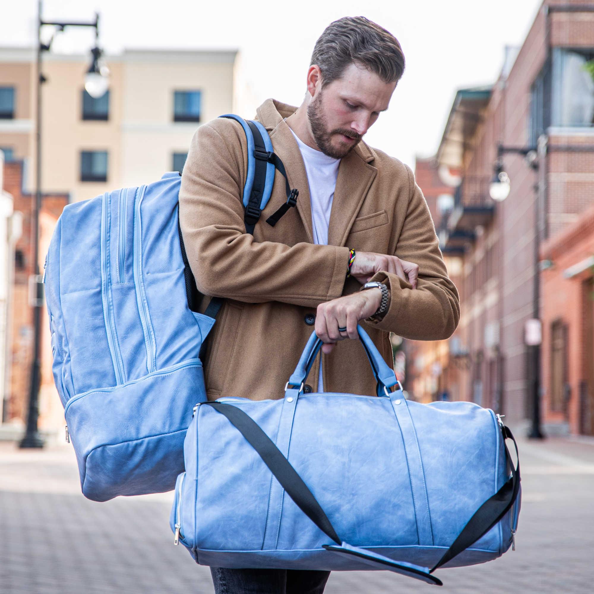 Man holding a blue duffel bag on a city street