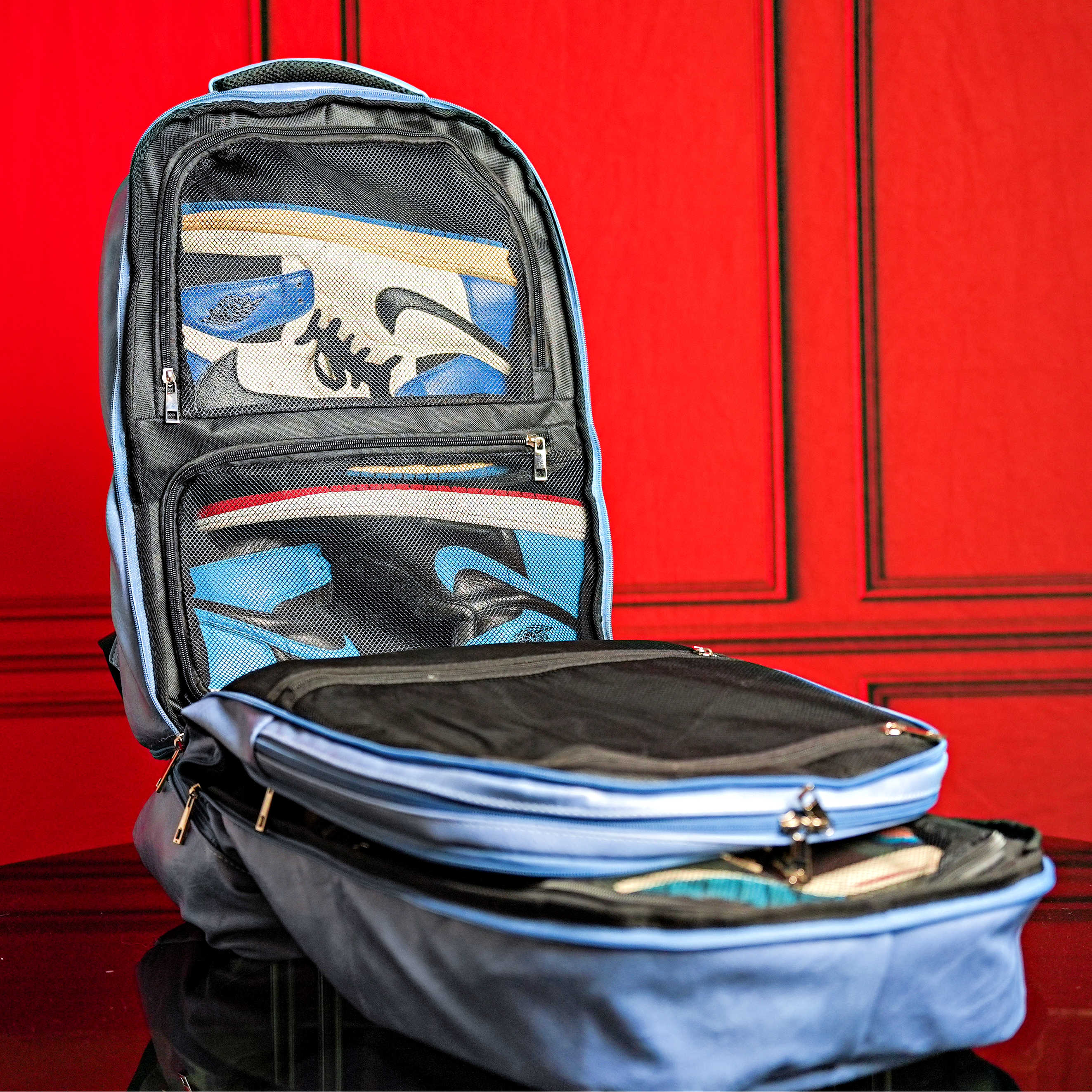 Open backpack with items inside against a red background