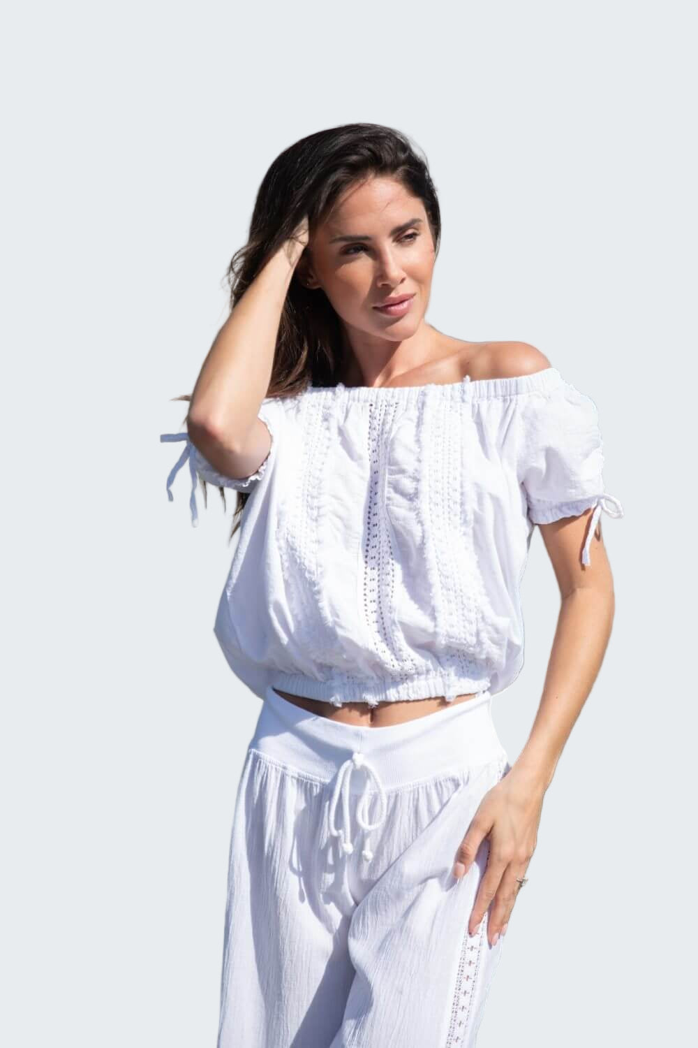 Woman in a white outfit standing by a boat on a dock.