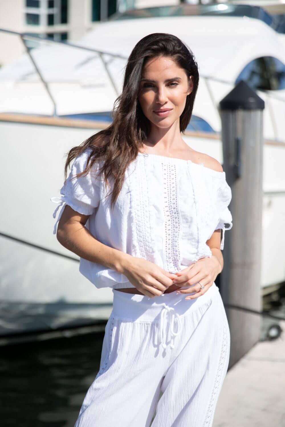 Woman in a white outfit standing by a boat on a dock
