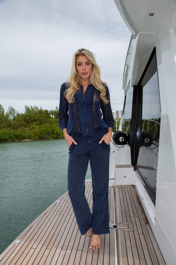 Woman in navy outfit standing on a dock next to a yacht