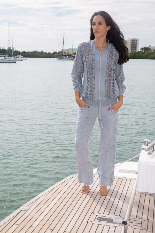 Woman standing on a dock by a body of water wearing a light gray outfit.
