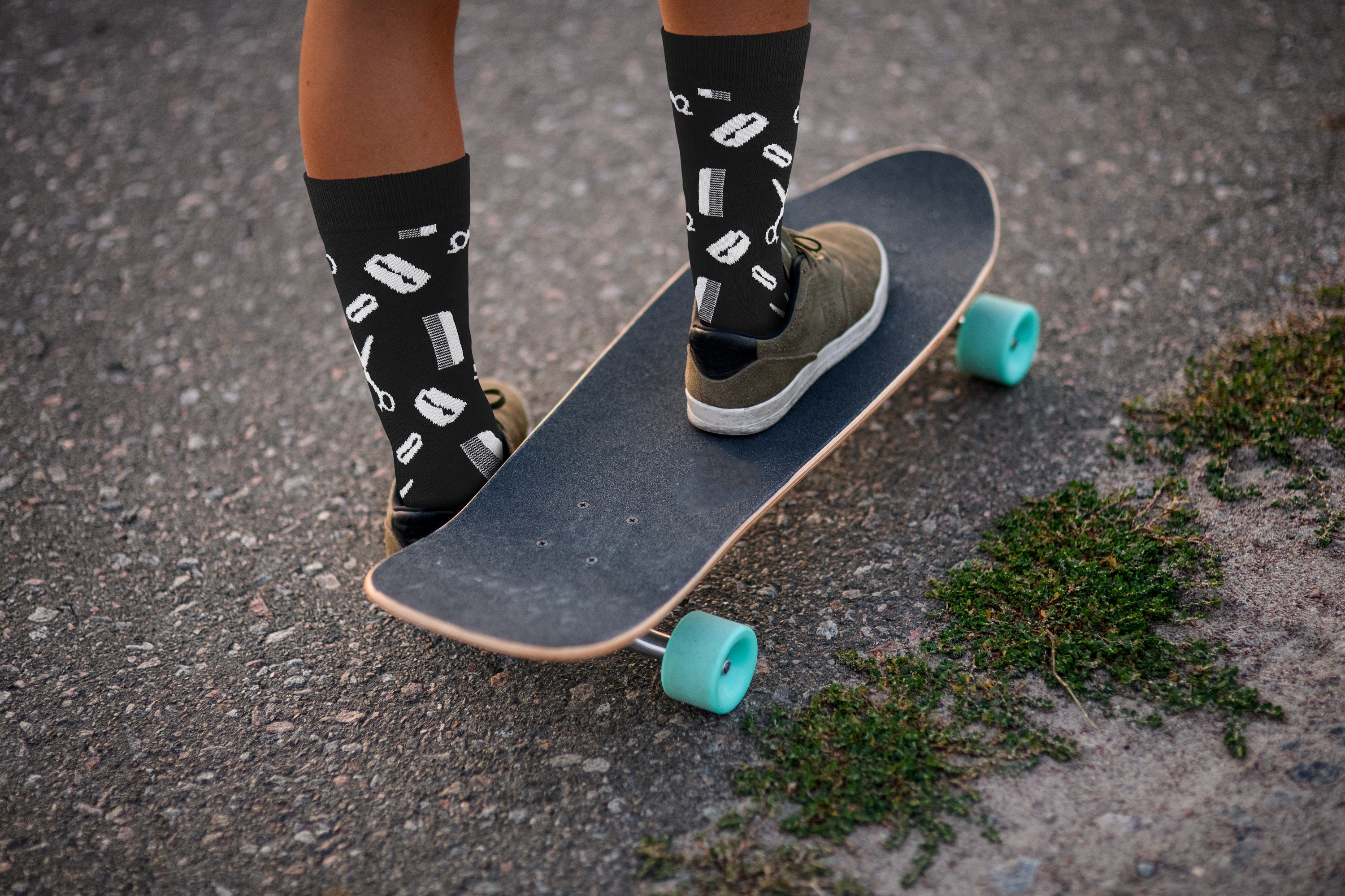 Person standing on a skateboard with patterned socks and turquoise wheels.