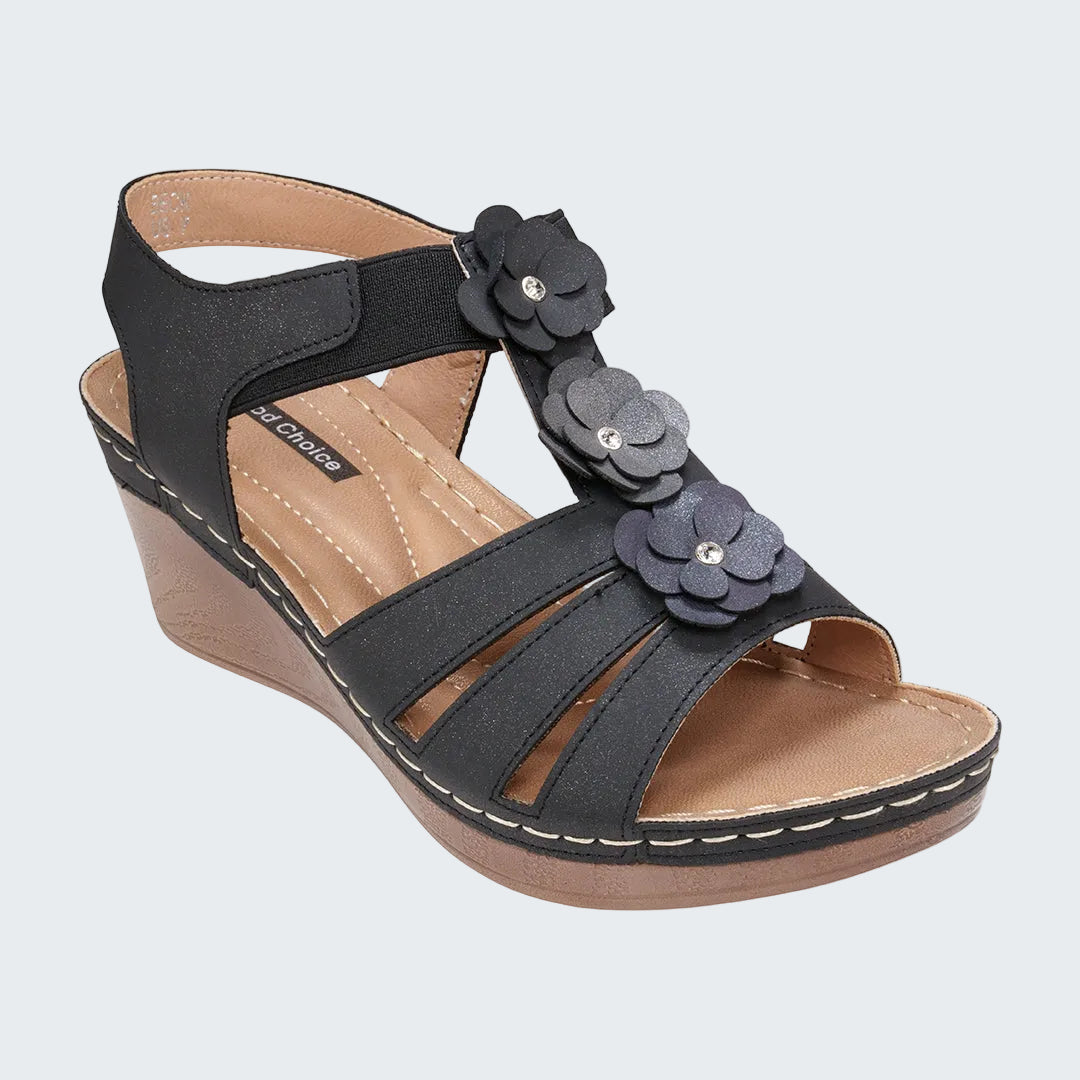 Black wedge sandal with floral decorations on a white background
