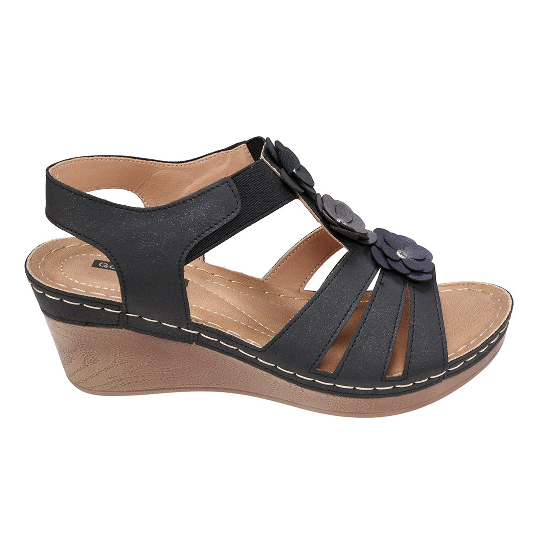 Black wedge sandal with floral details on a white background